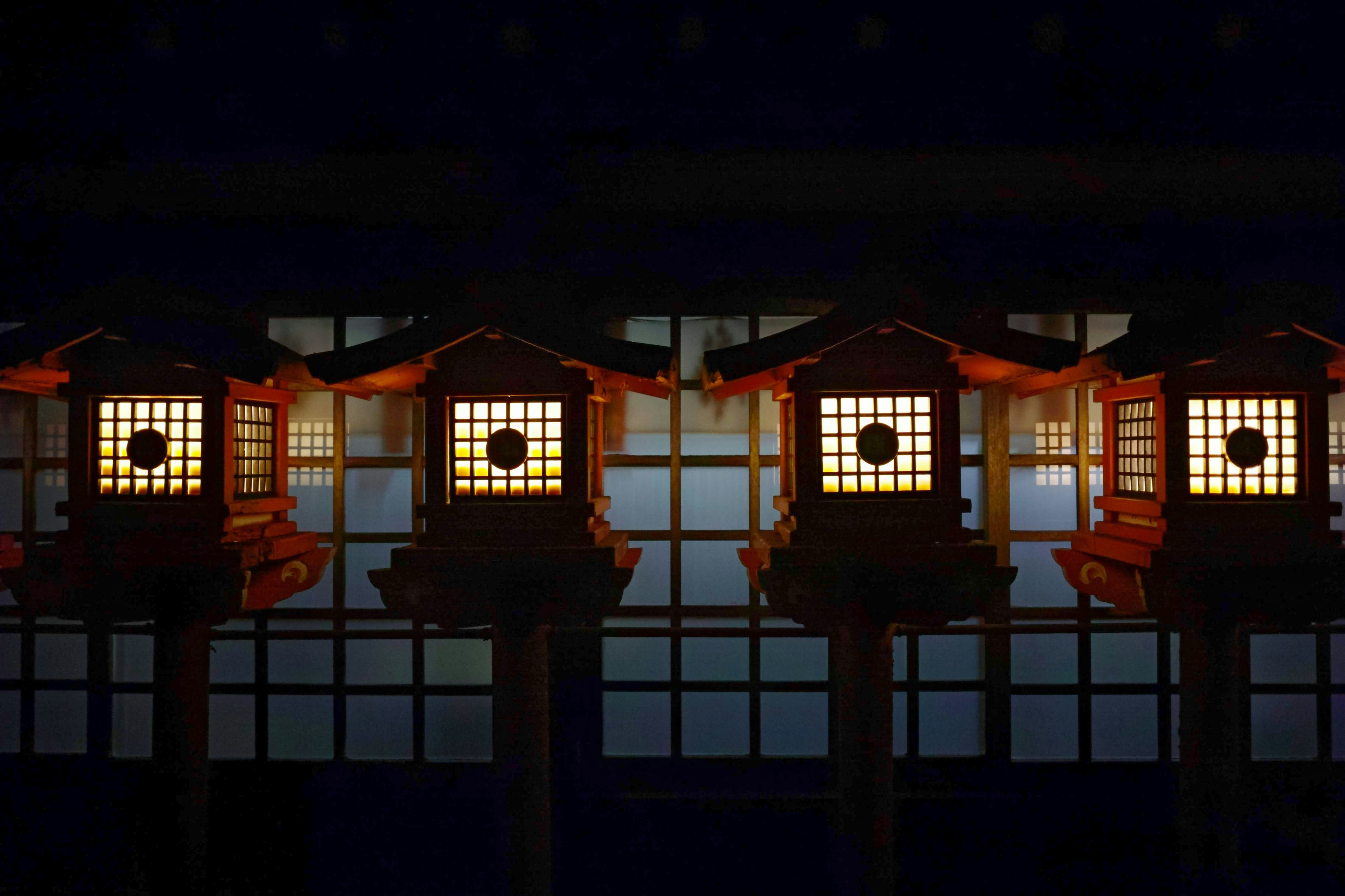 明るい灯篭が並ぶ神社の回廊の夜景