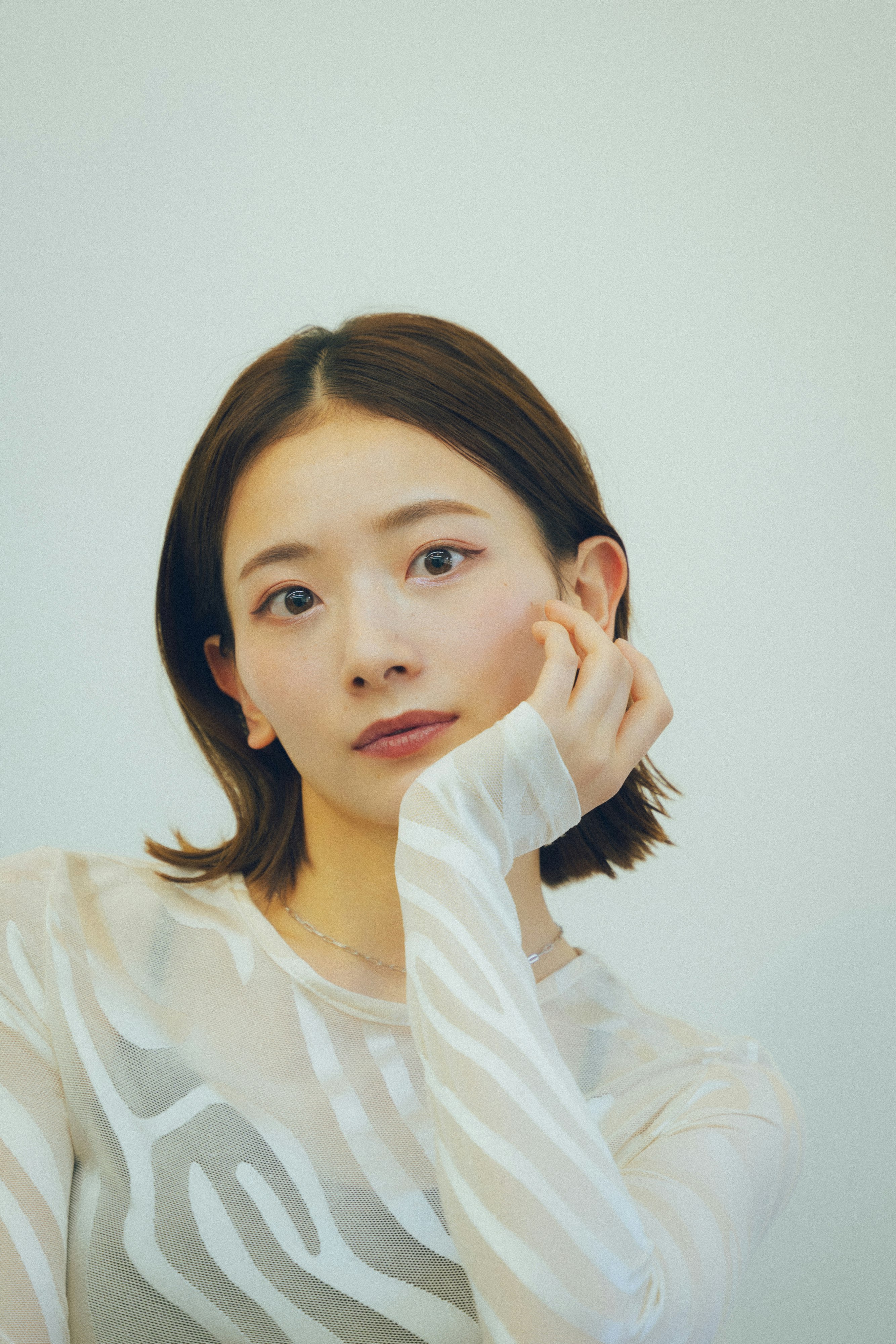 白色衬衫的女性手托脸颊的肖像