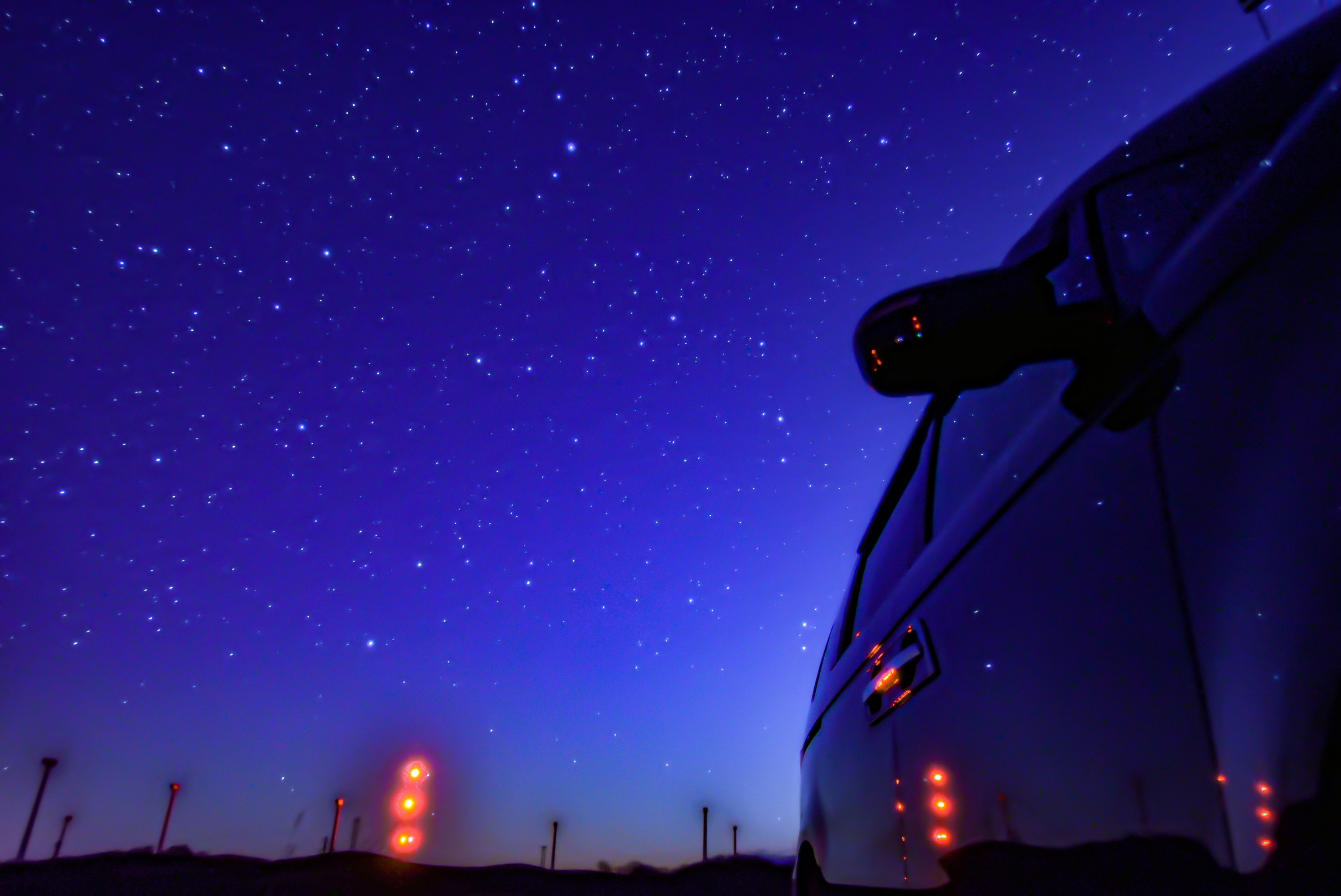 夜空に浮かぶ星と街灯の並ぶ道路の先の風景