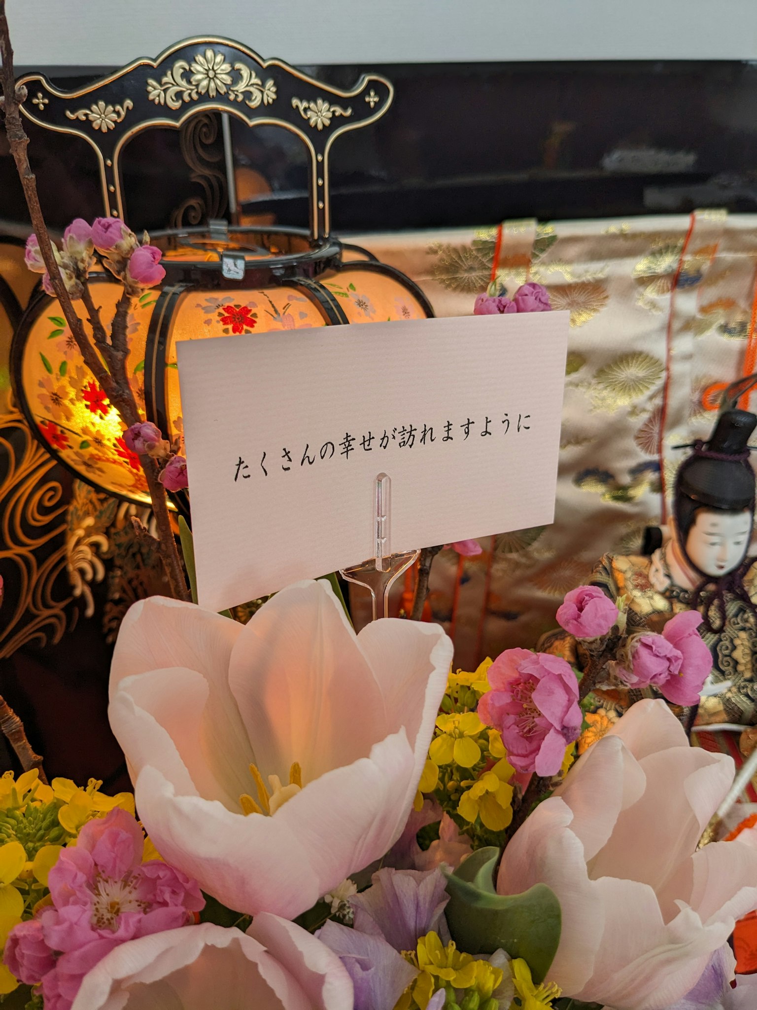 Sebuah altar dekoratif dengan bunga-bunga cerah dan kartu pesan di depannya