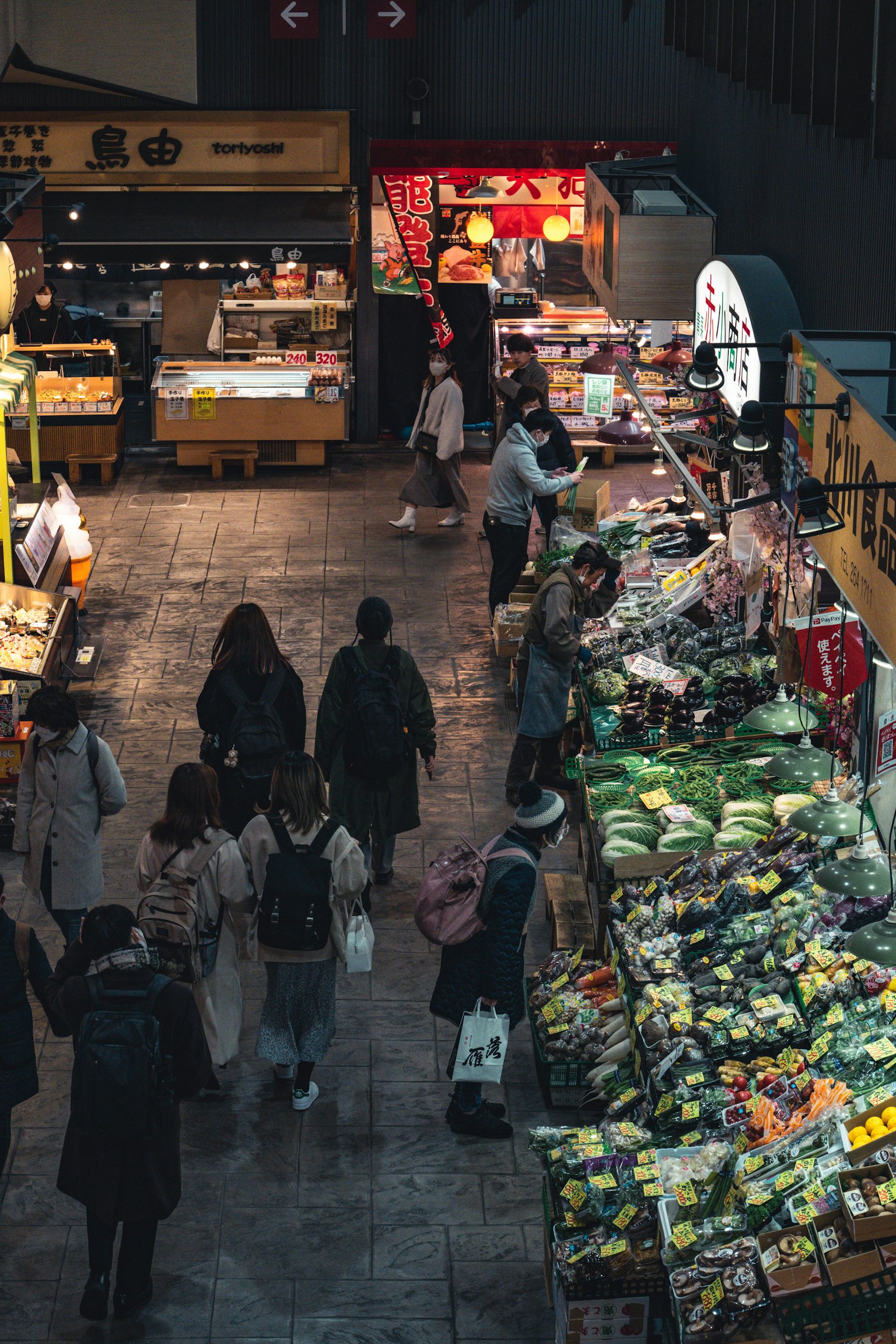 Scena di mercato al coperto con acquirenti e frutta e verdura fresche in esposizione