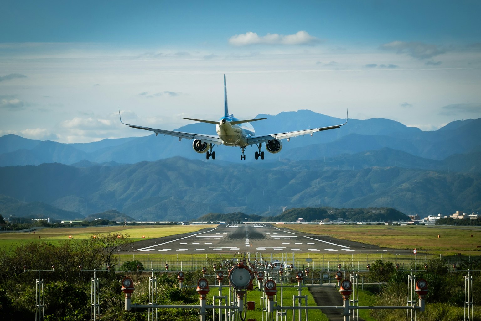 Airplane landing on runway with mountains and blue sky in the background