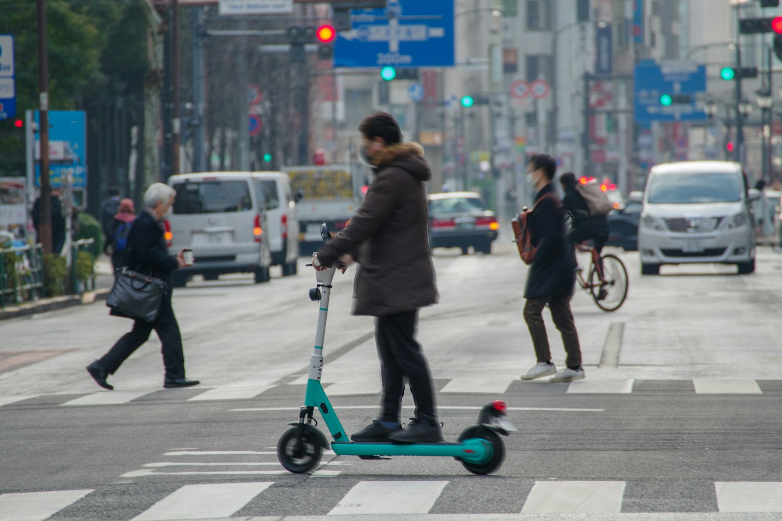Homme sur un scooter électrique à un passage piéton en ville avec des piétons