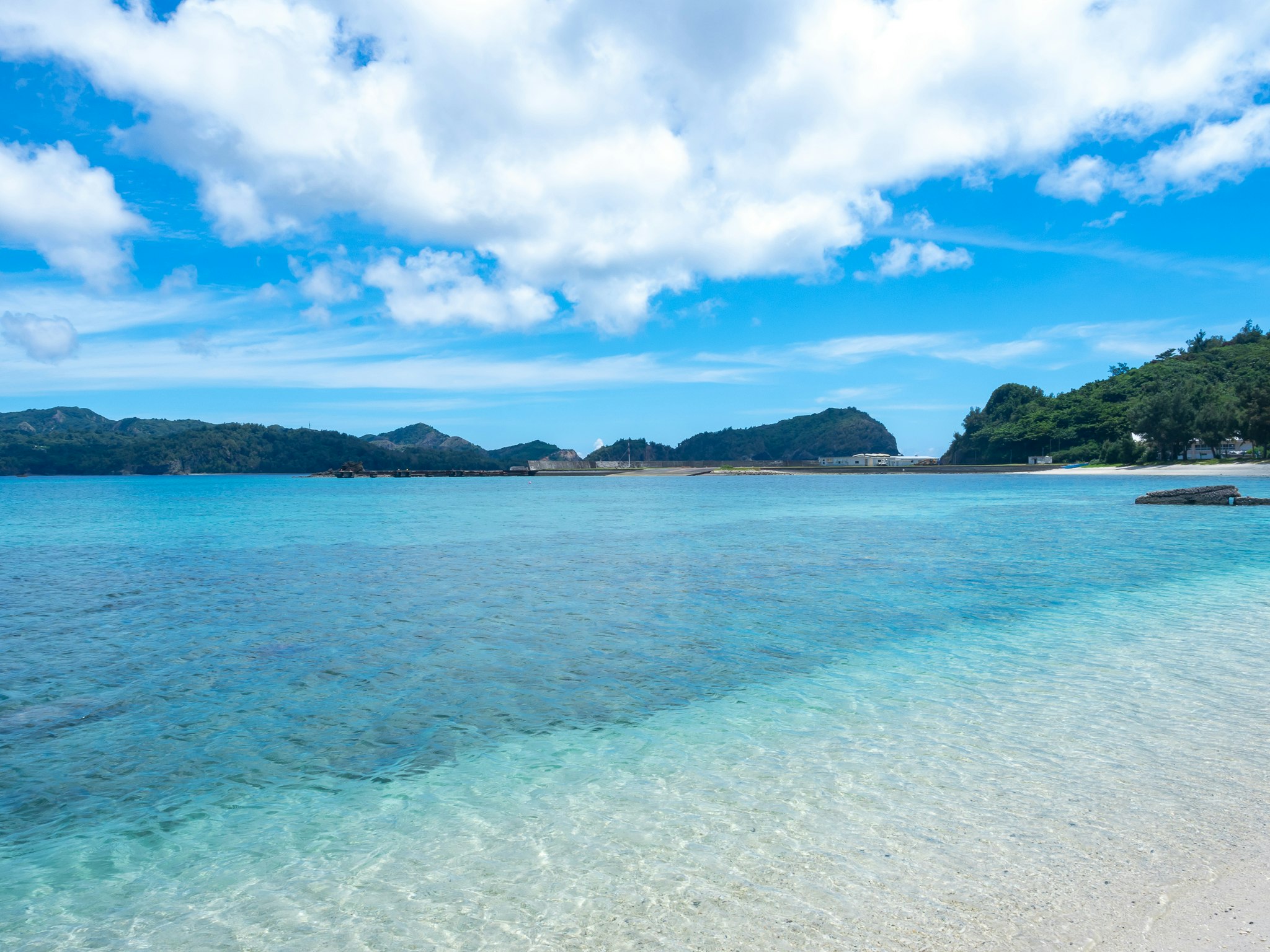 透き通る海と遠くの島影が広がる海岸の風景