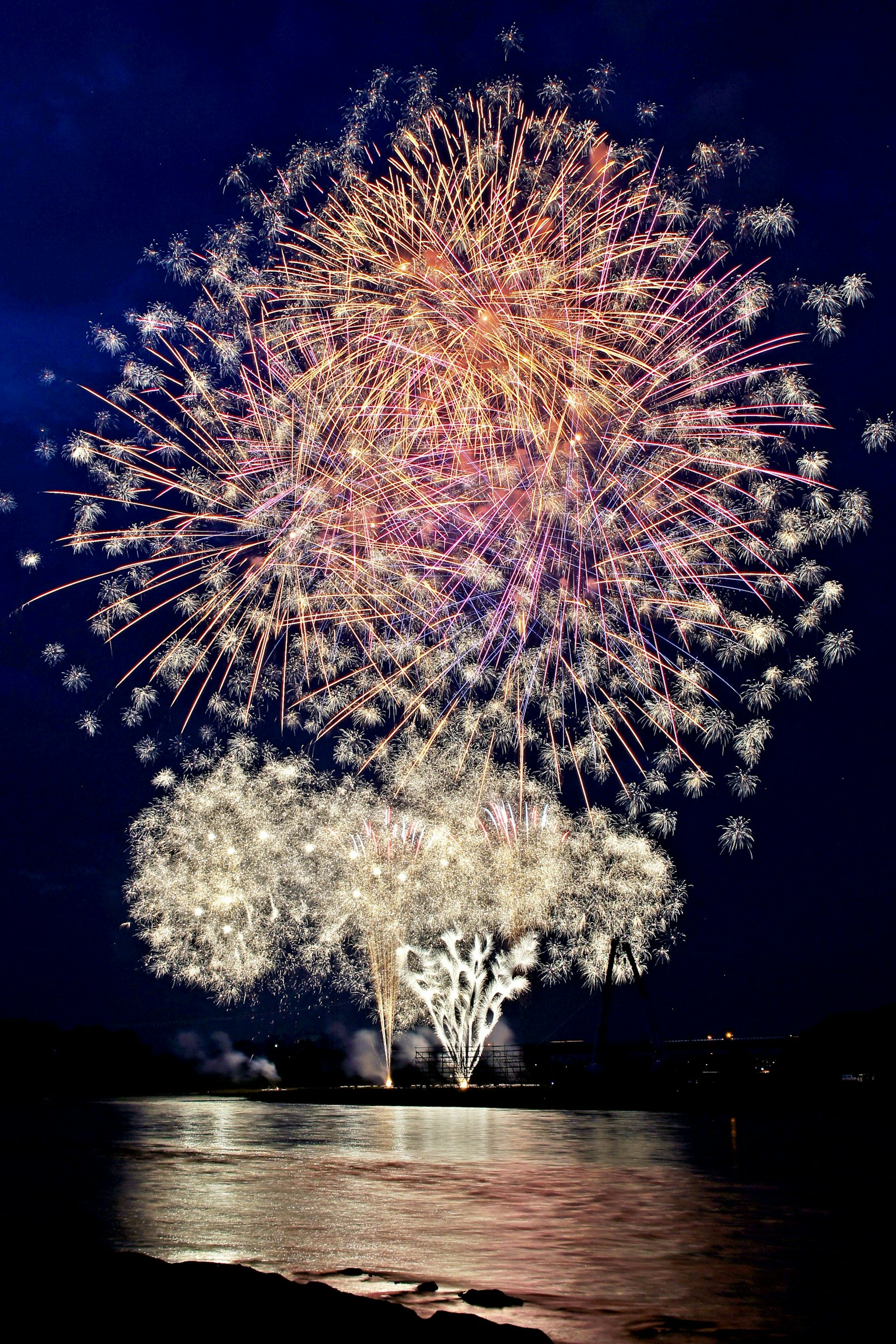 Colorful fireworks display illuminating the night sky reflections on the water