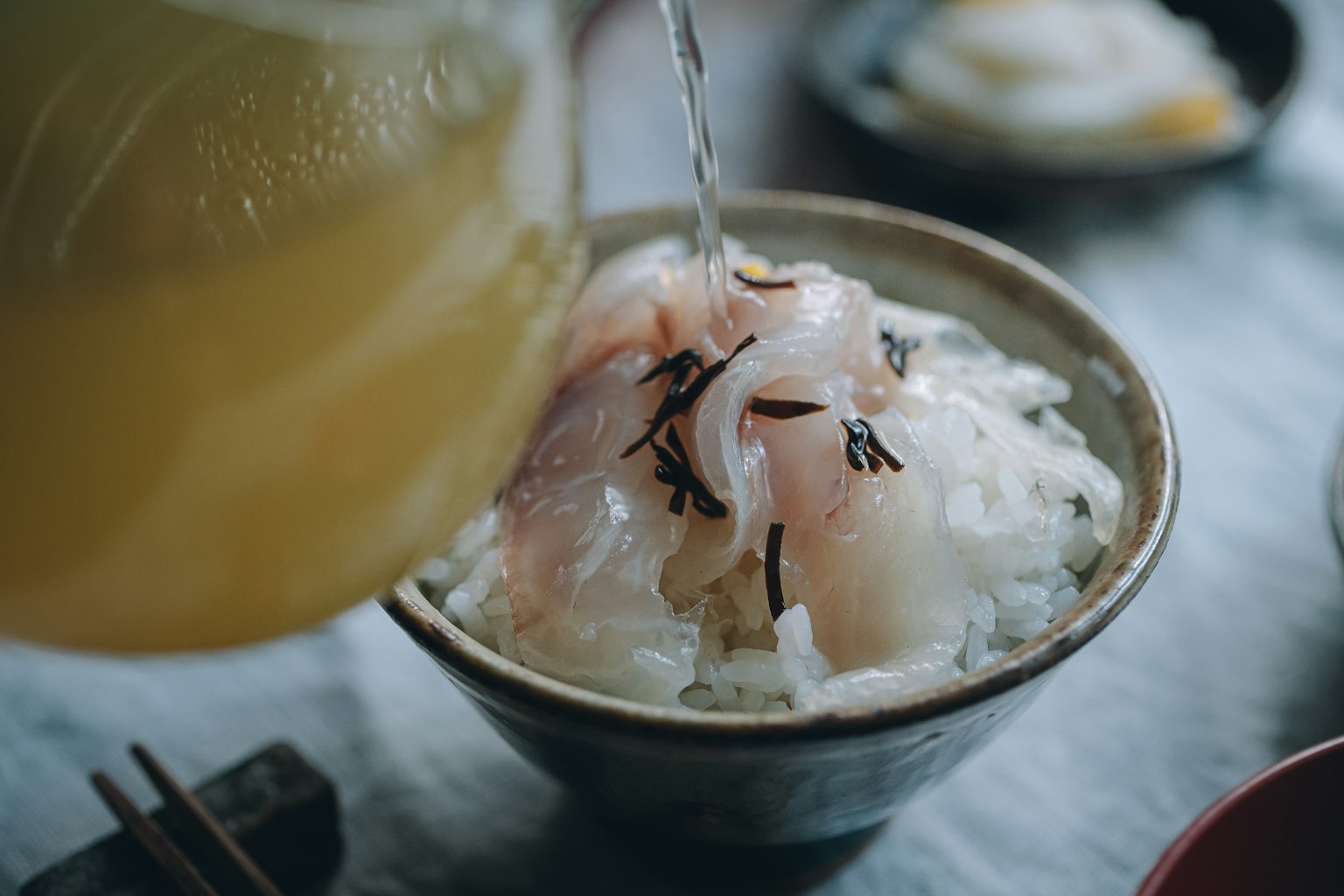 Eine Schüssel Reis mit frischem Sashimi, in die Brühe gegossen wird