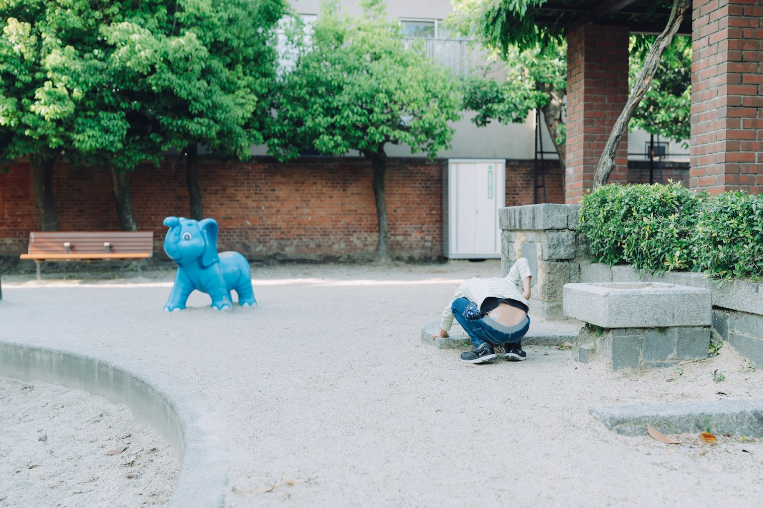 공원에 있는 파란색 코끼리 조각과 그 근처에서 노는 아이