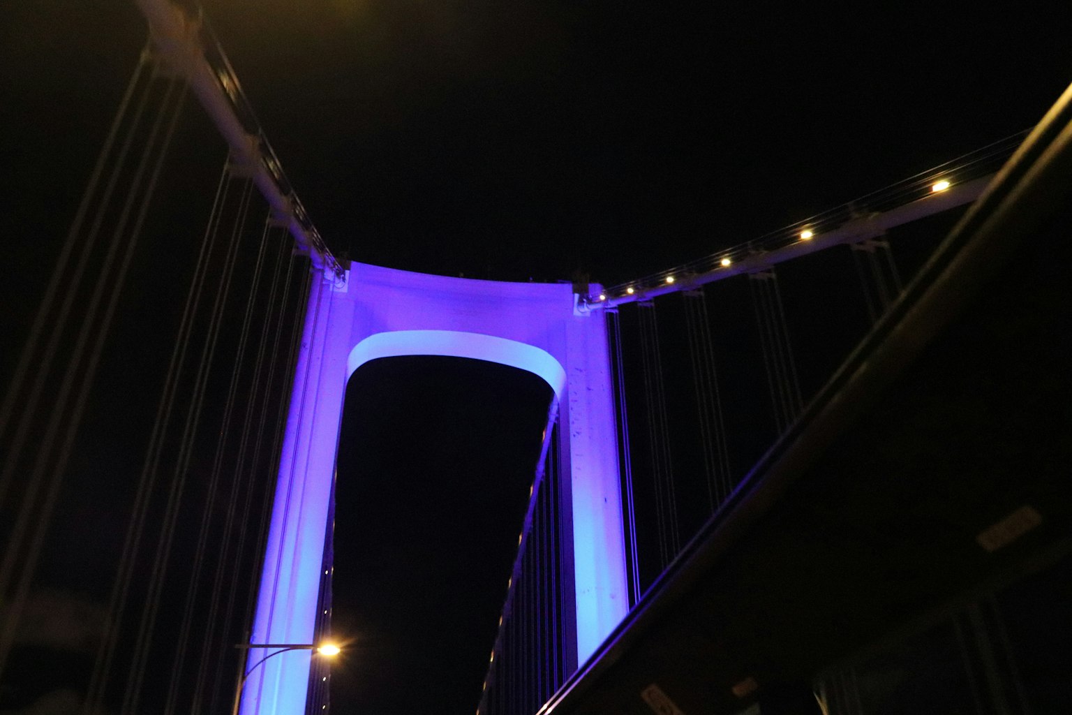 Arco de un puente iluminado de púrpura por la noche