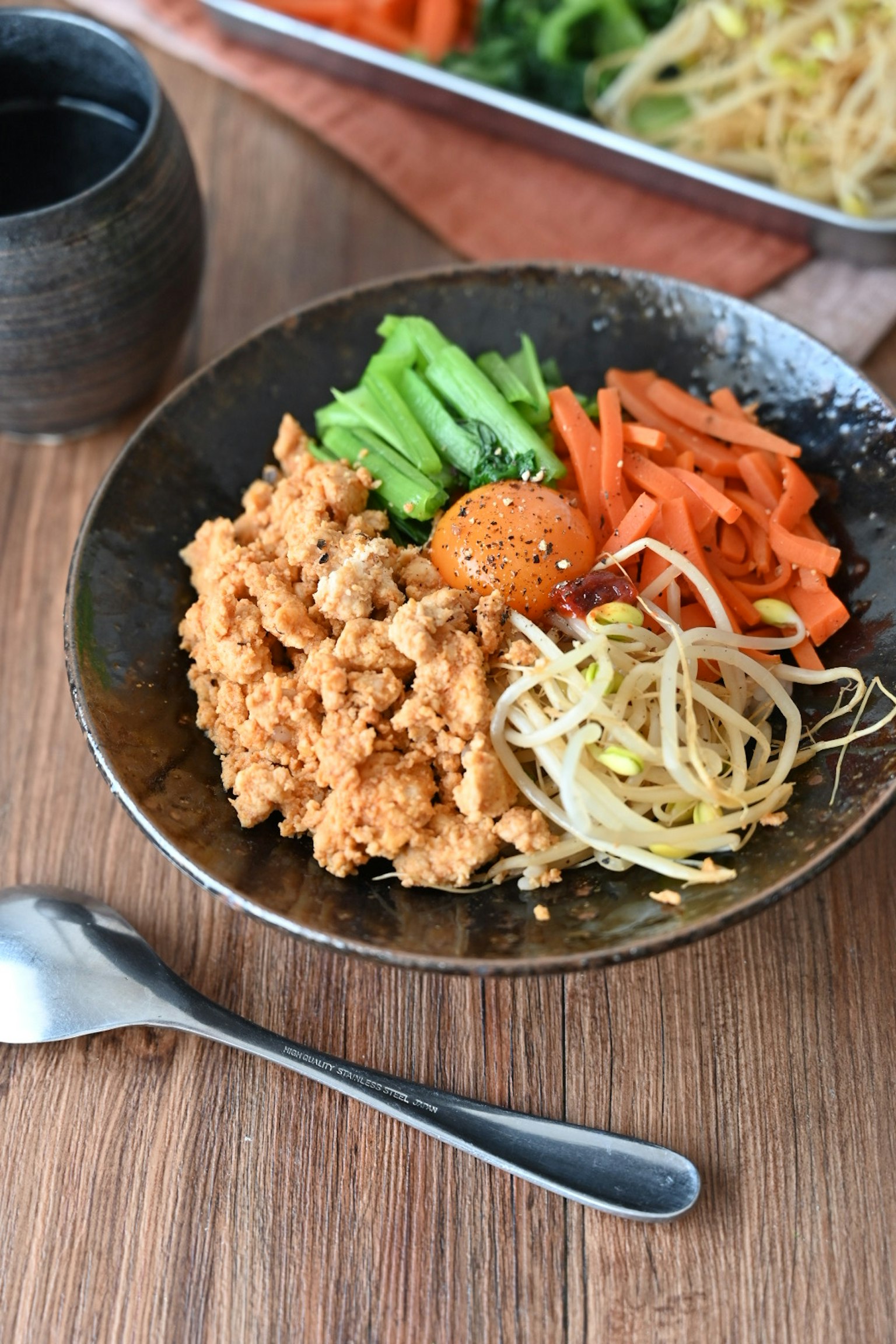 Un plat de bibimbap coréen coloré servi dans un bol noir avec divers légumes et un œuf