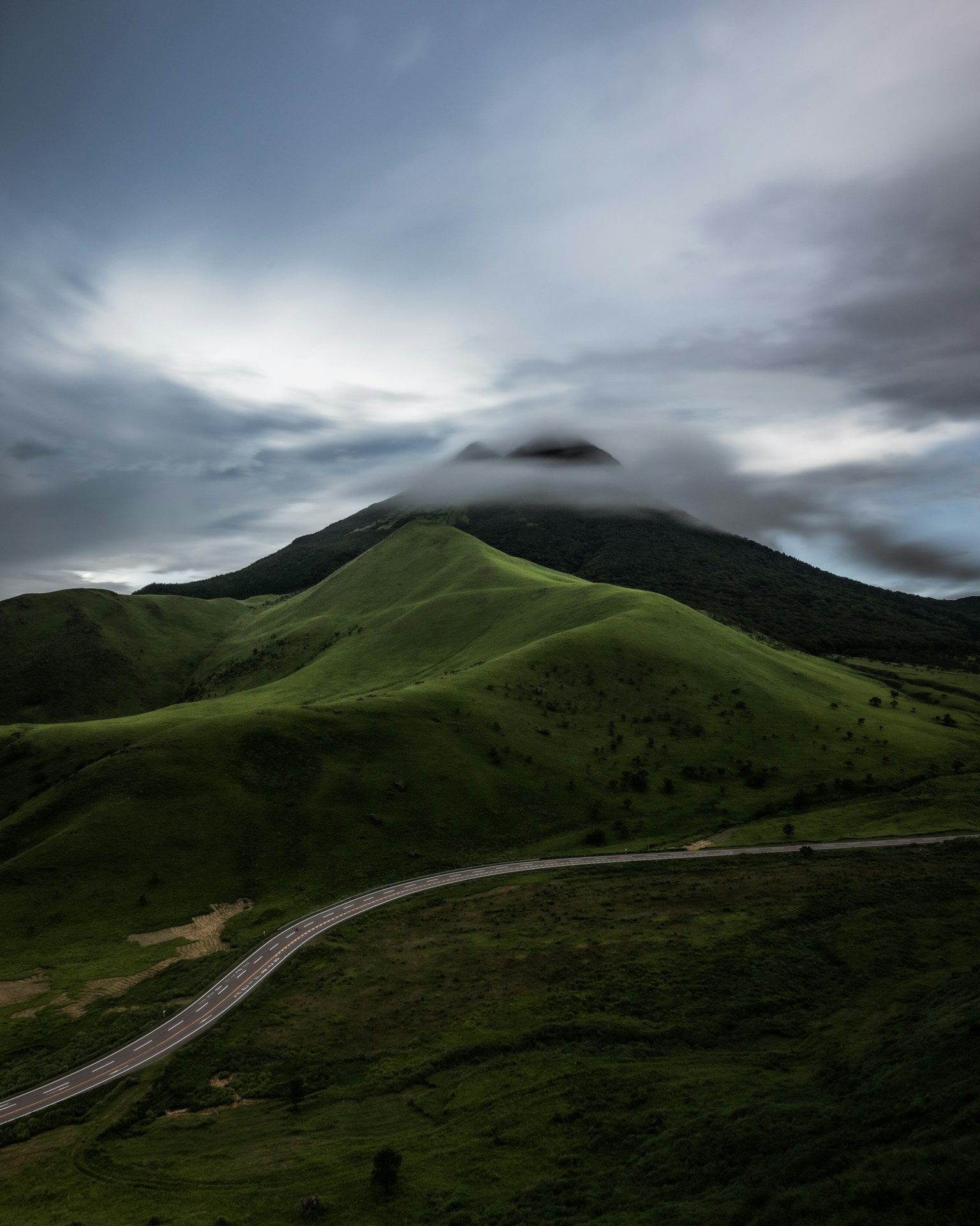 Vista panoramica di colline verdi e una montagna avvolta nelle nuvole