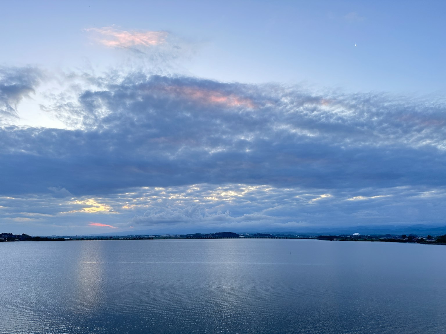 Lago tranquillo che riflette il cielo blu e le nuvole