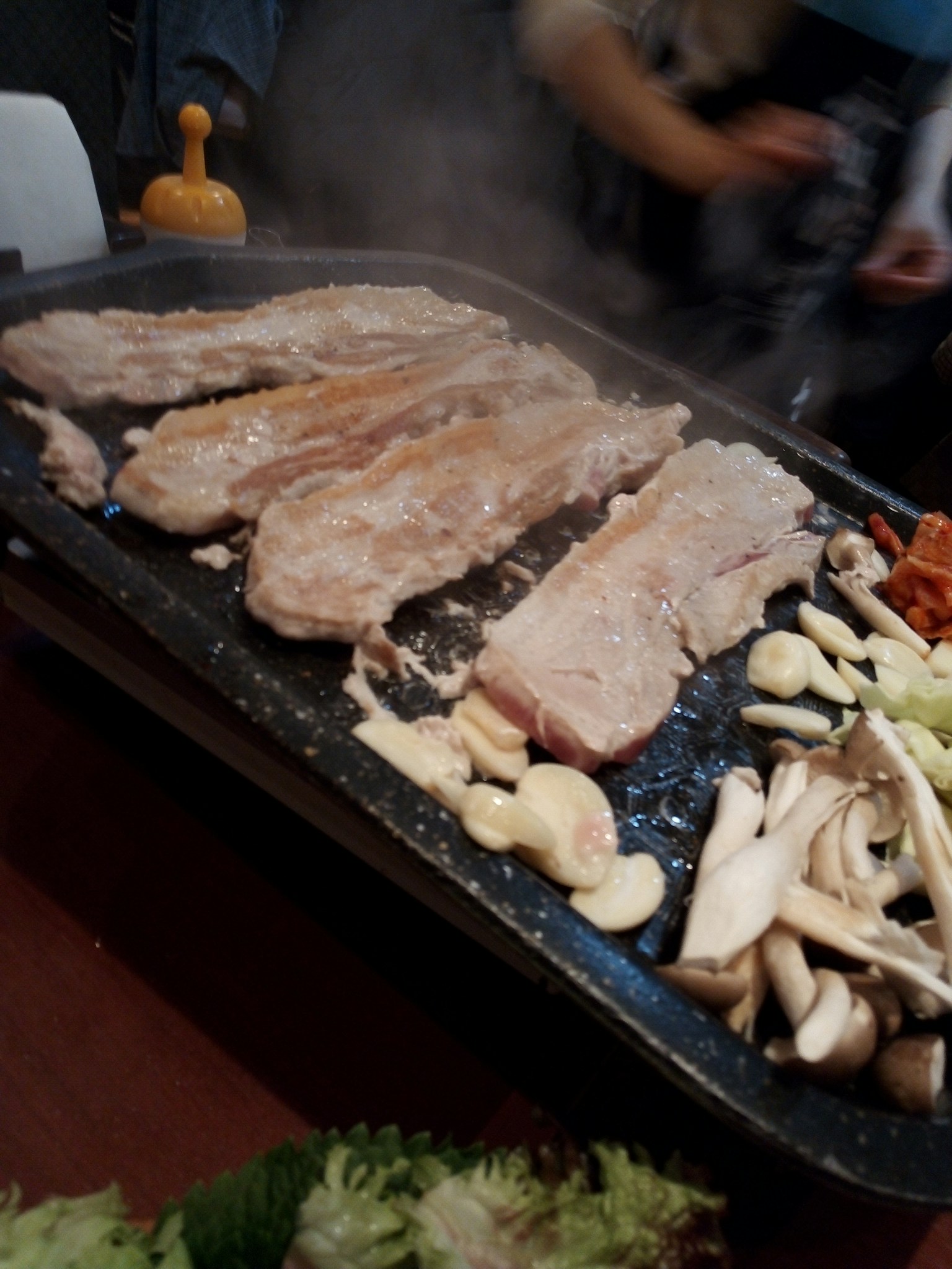 烤肉和蔬菜在冒着蒸汽的烤盘上