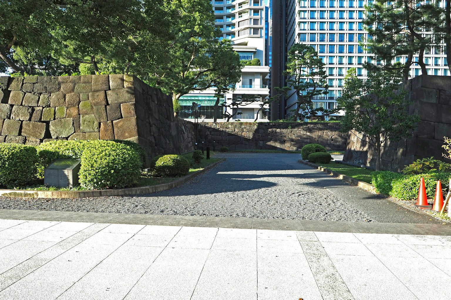 圍繞著石牆的寧靜公園入口，綠樹成蔭和鋪裝小路