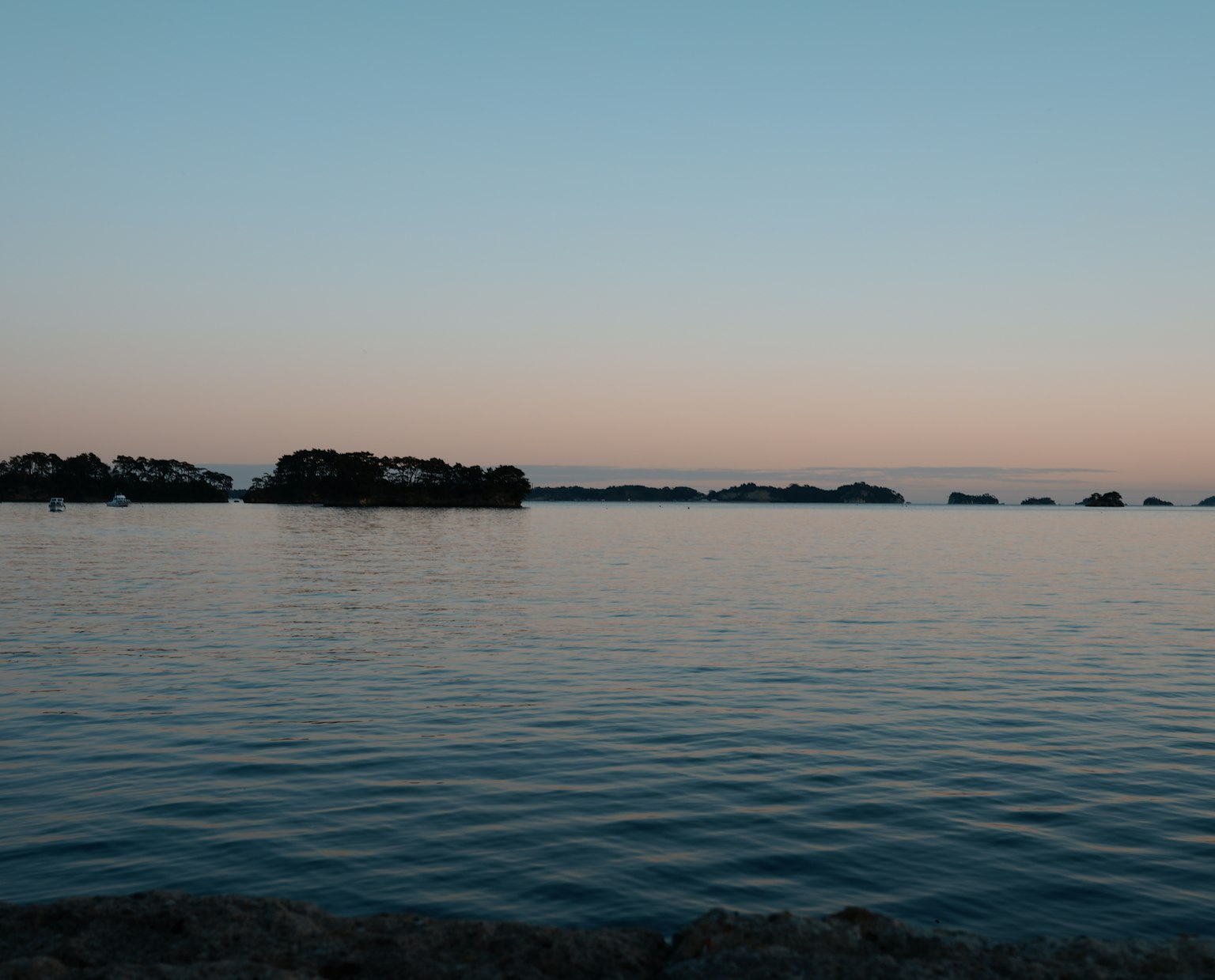 Superficie d'acqua serena con tonalità morbide del cielo in una scena costiera tranquilla