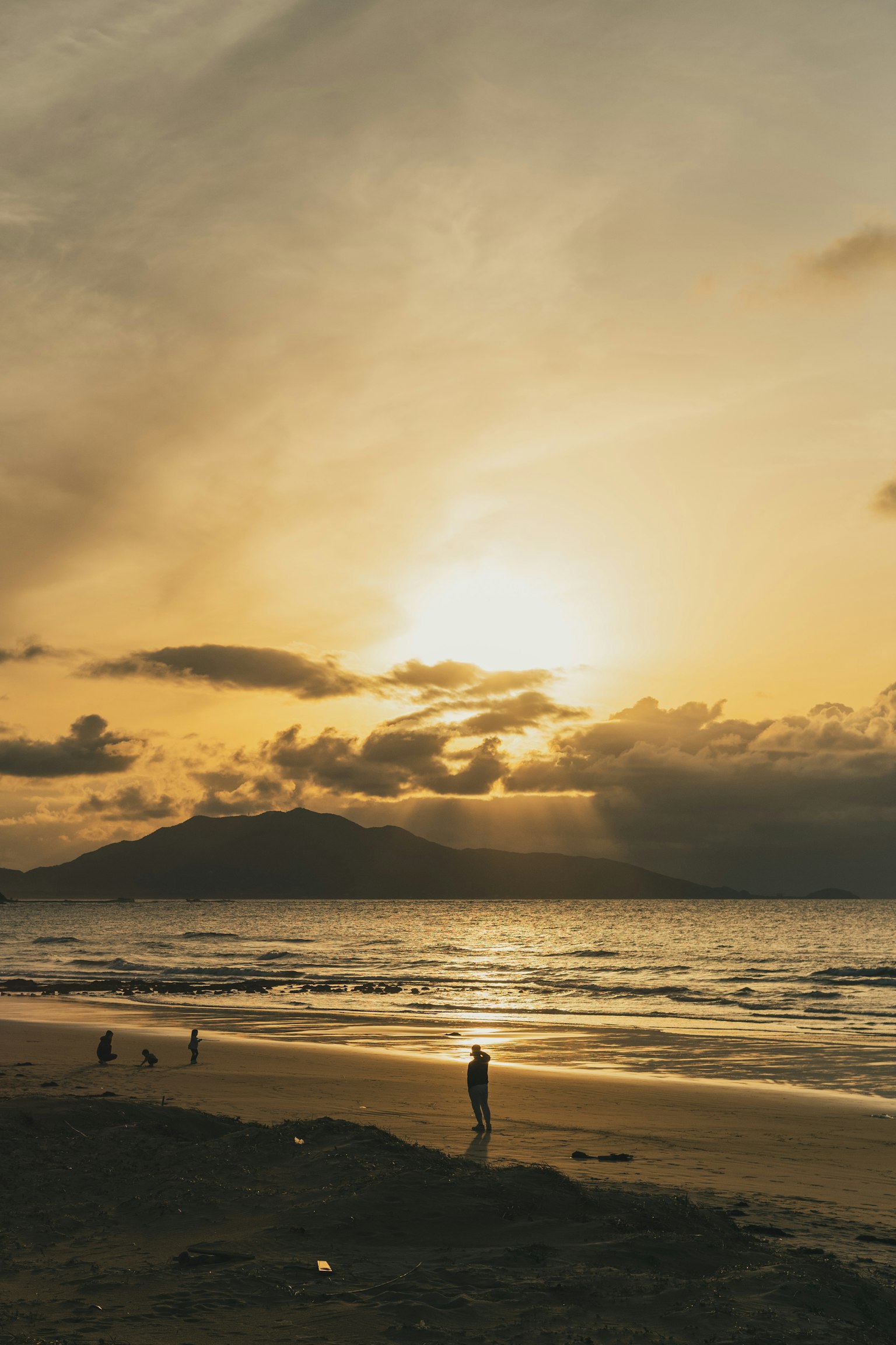 美しい夕焼けの海岸に立つ人影と遠くの山