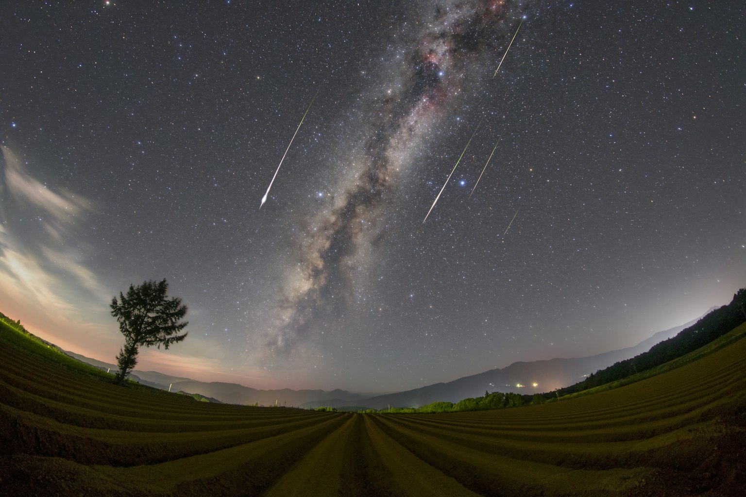 Paisaje rural bajo un cielo estrellado con la Vía Láctea