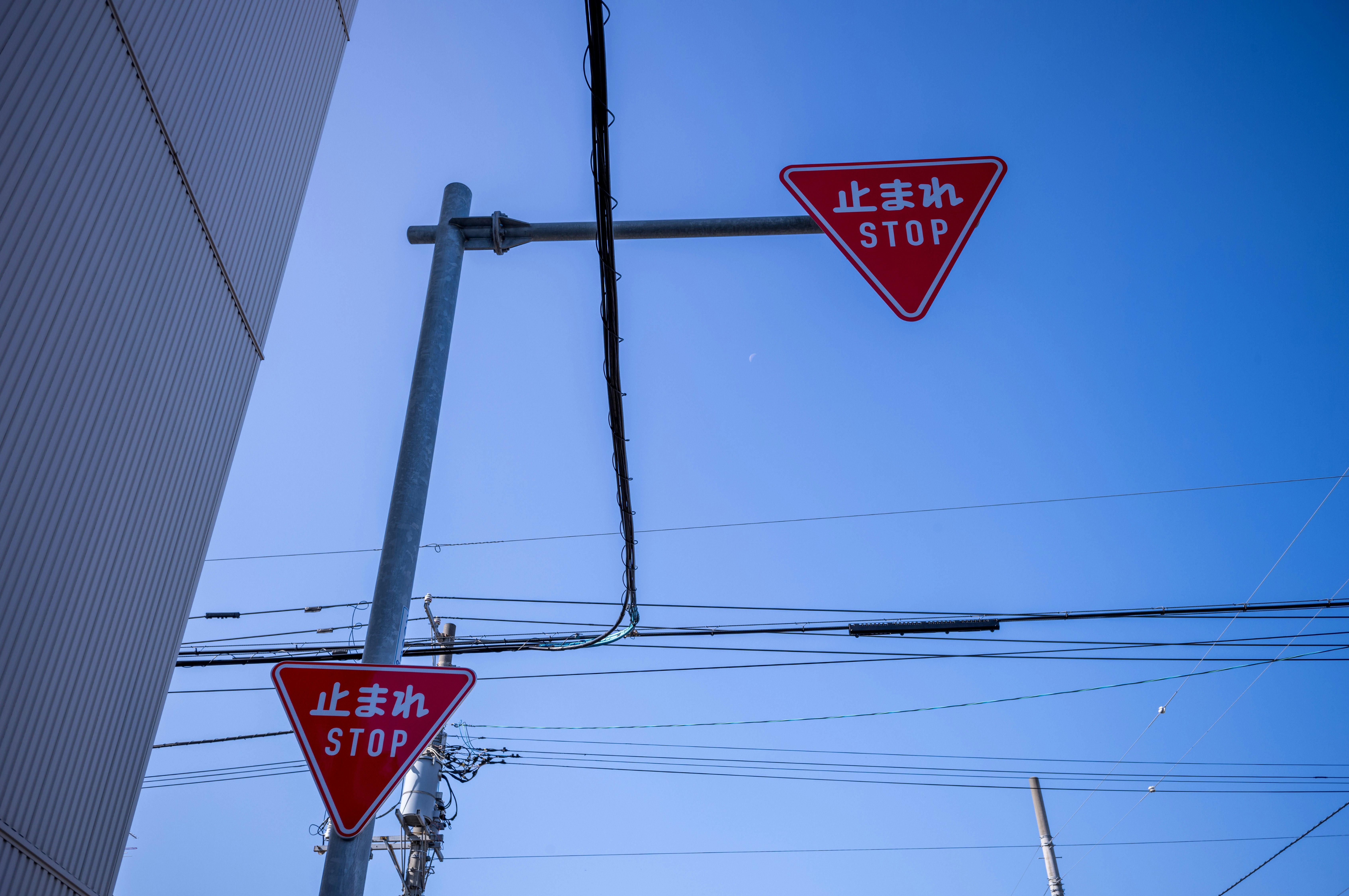 Stop sign and overhead wires under a clear blue sky