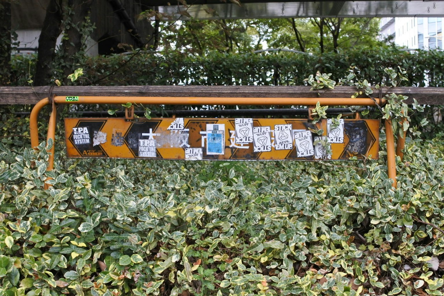 Barre métallique orange entourée de verdure avec des notes et des affiches attachées