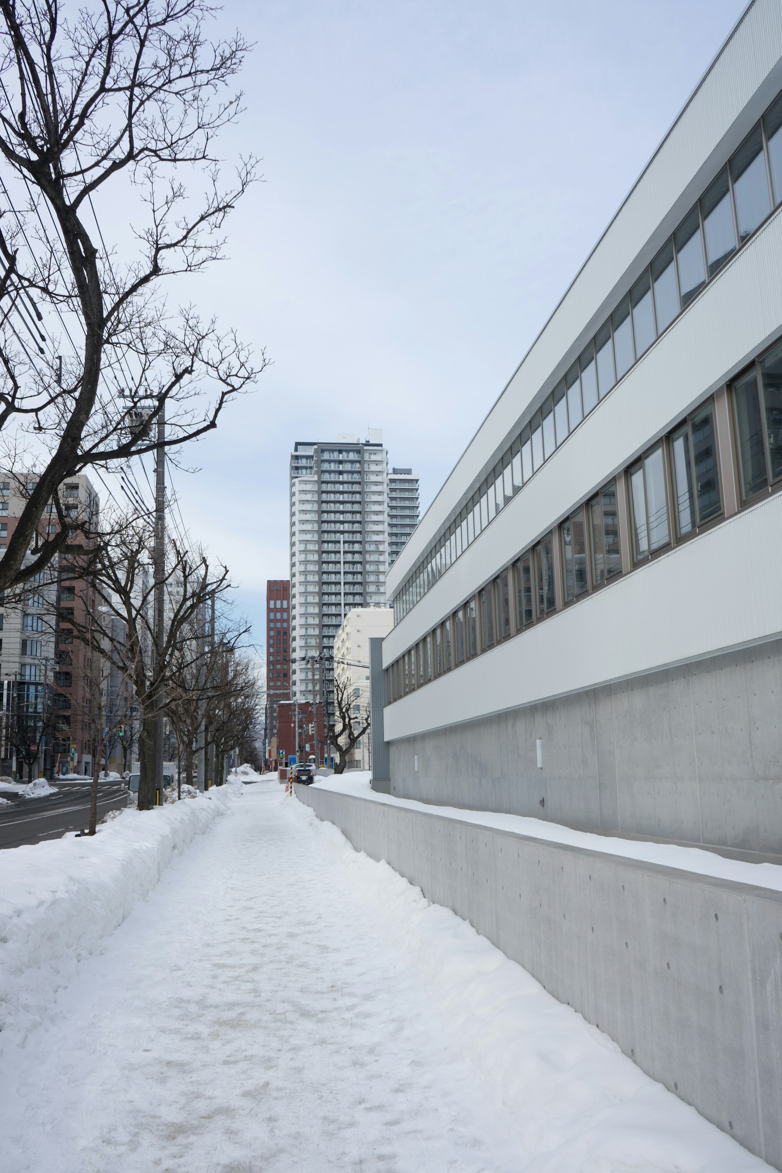 Schneebedeckter Gehweg mit modernen Gebäuden entlang der Straße