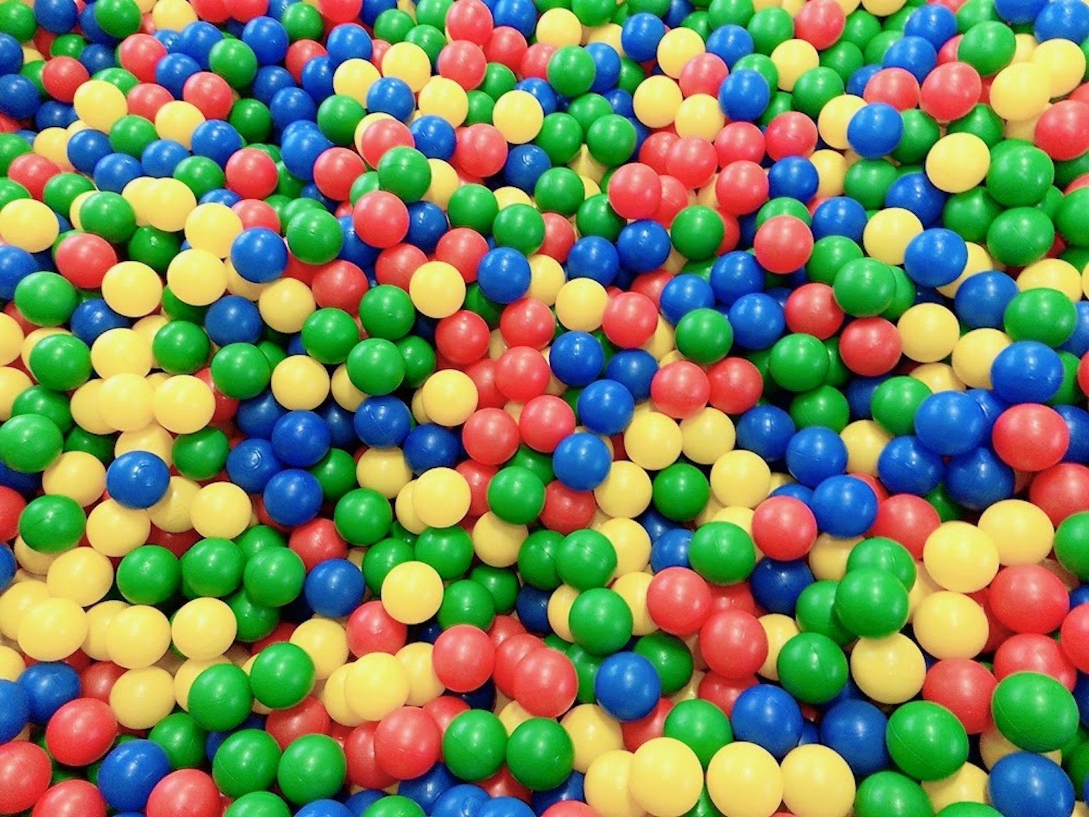 Colorful balls in a ball pit filled with red, blue, green, and yellow spheres