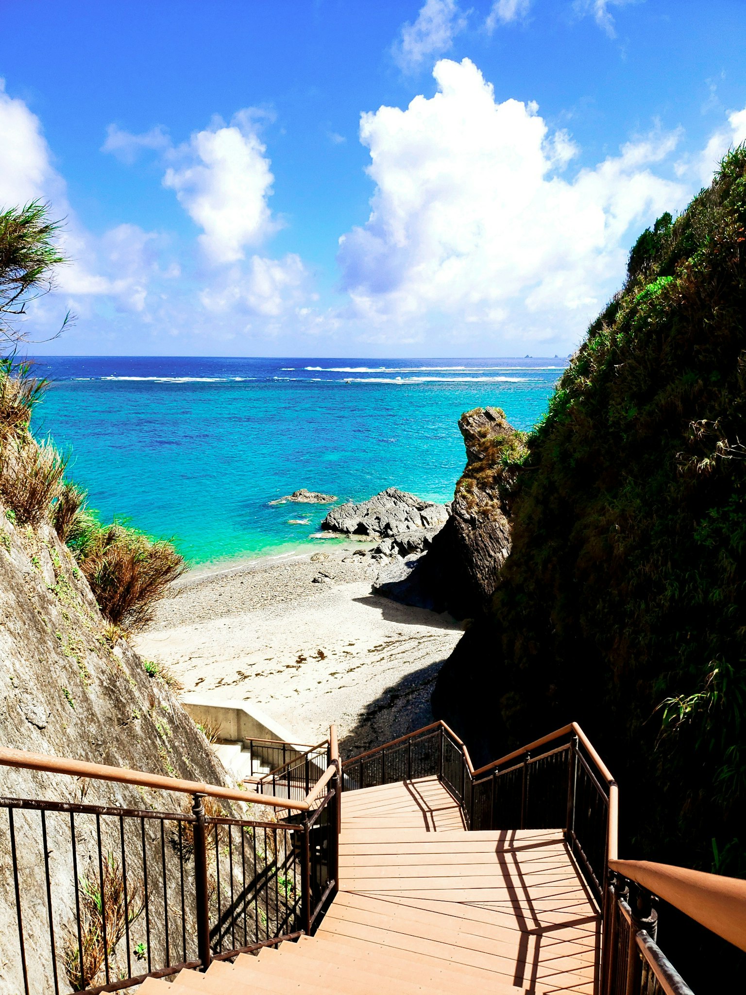 Scala che porta a una bellissima spiaggia con acqua turchese e cielo blu