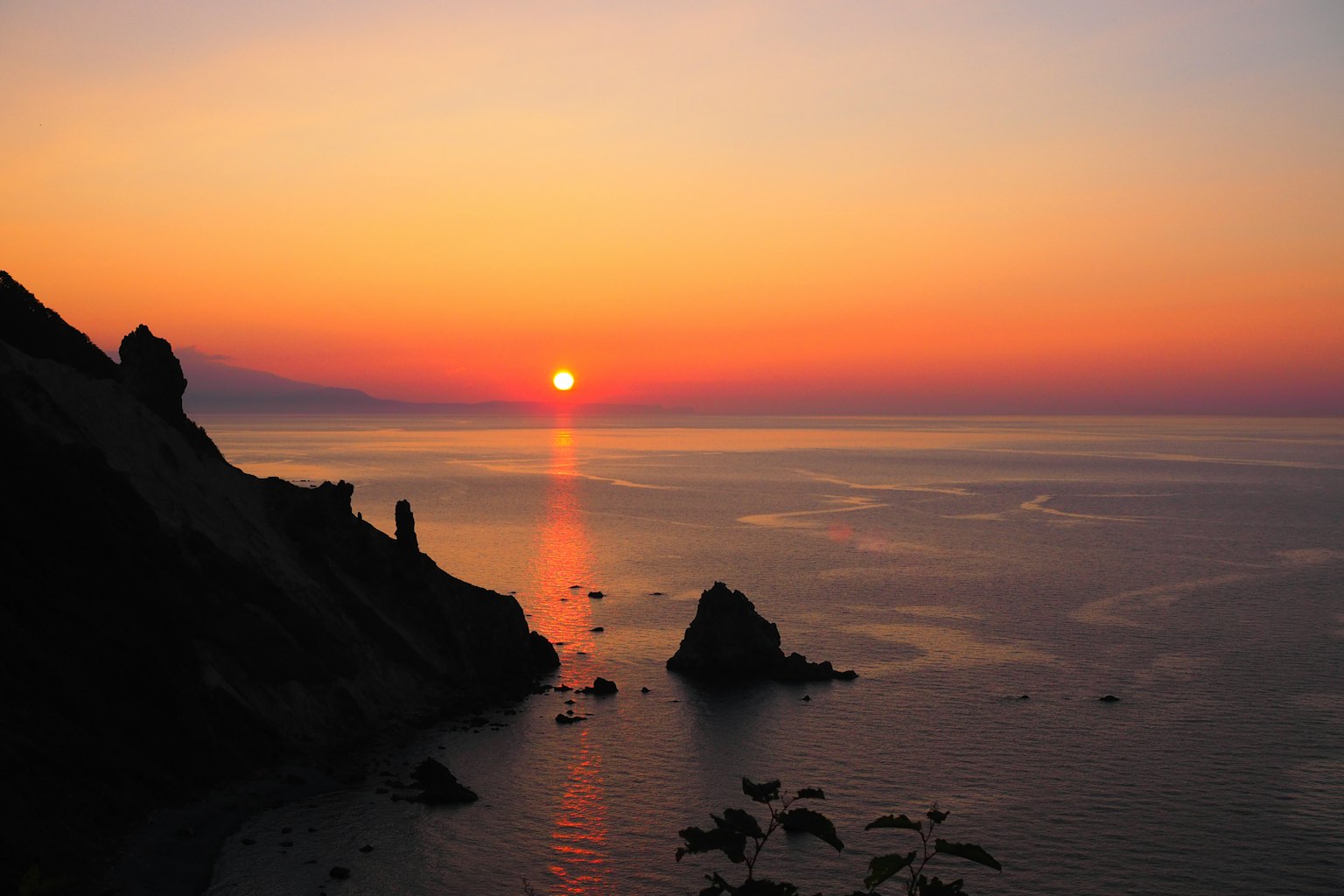 Stunning sunset over the ocean with silhouettes of rocks