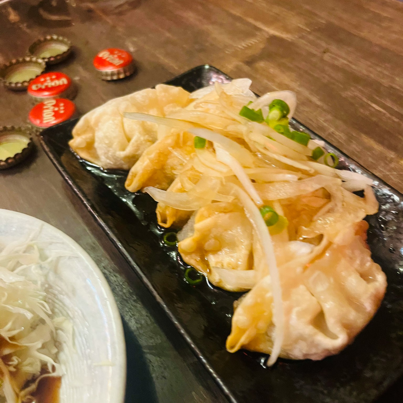 Gyoza servi sur une assiette noire garni d'oignons verts