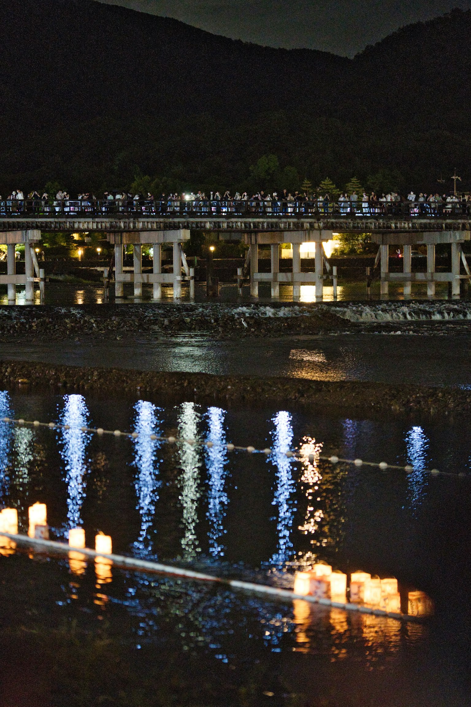 夜晚河面上漂浮的灯笼与周围建筑的倒影构成的美丽景象