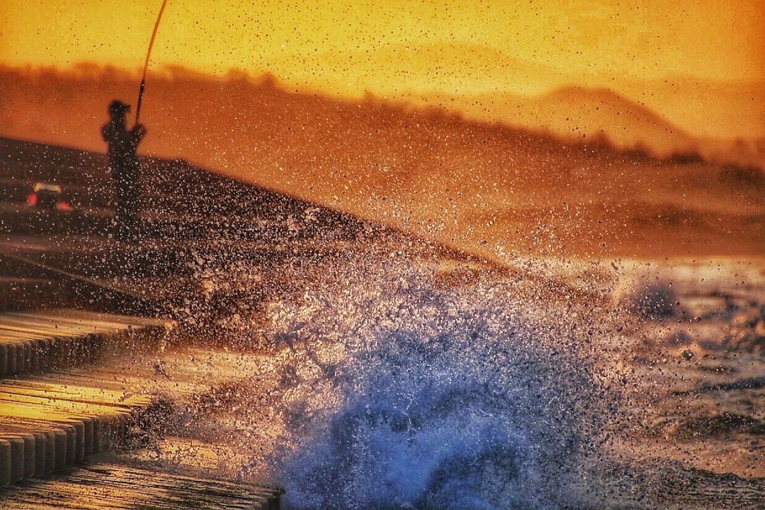 Eine Person angelt bei Sonnenuntergang mit spritzenden Wellen