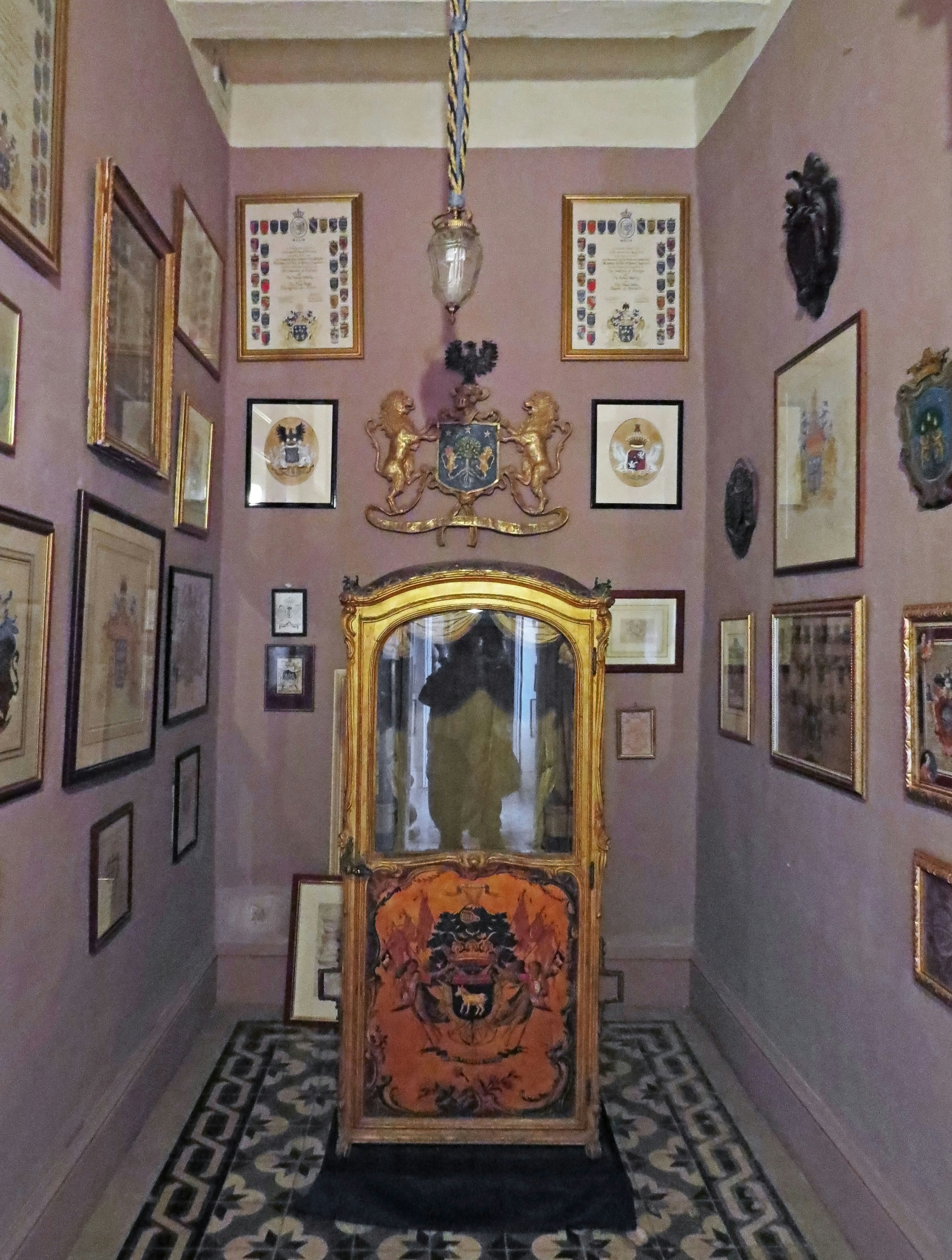 Couloir intérieur avec tableaux encadrés, miroir orné et chaise au style ancien