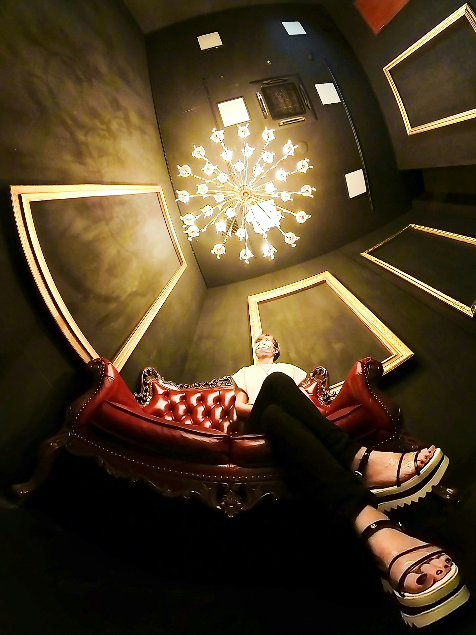 person relaxing on a studded sofa surrounded by framed wall art