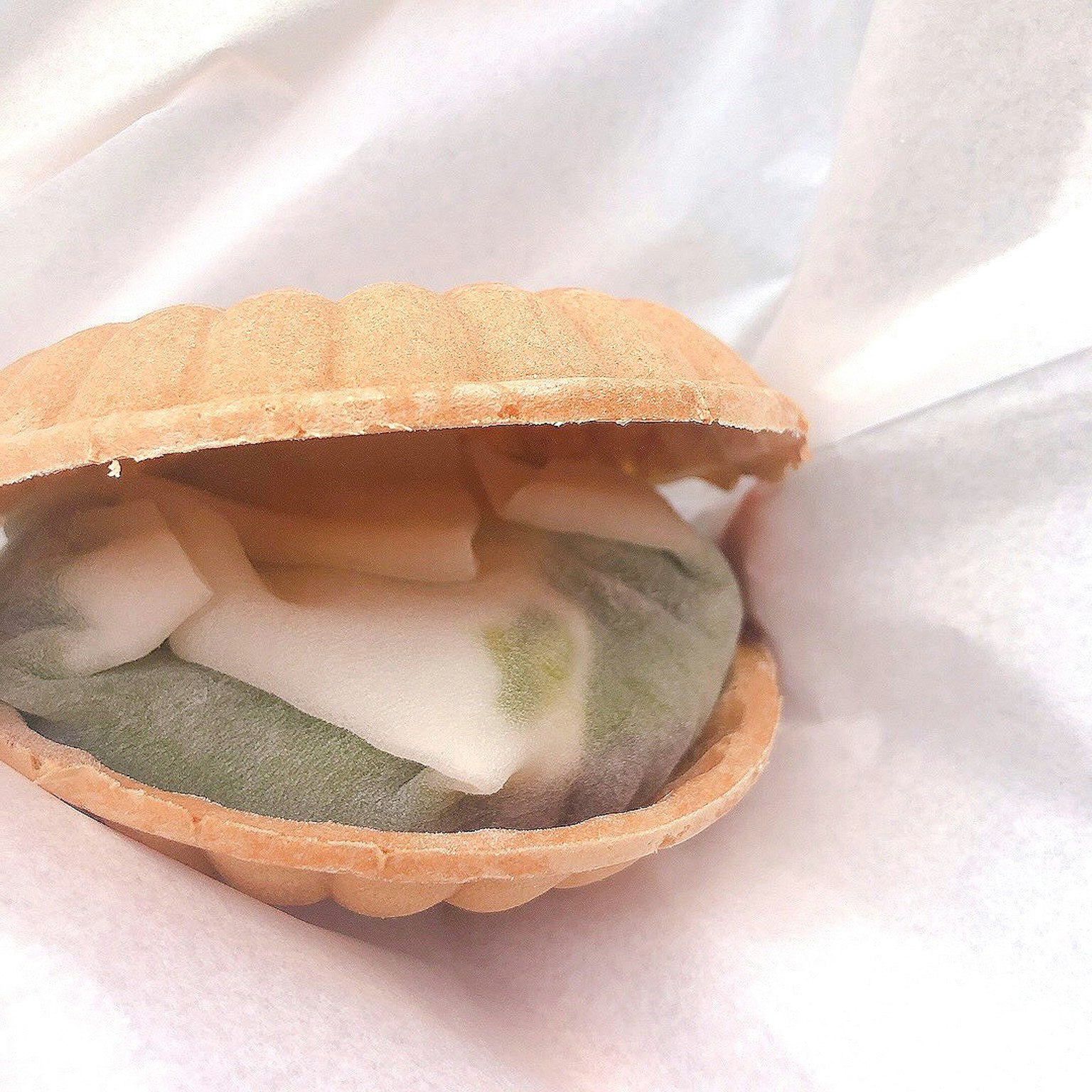 Un postre que parece helado envuelto en pasta de frijoles verdes dentro de una concha de waffle