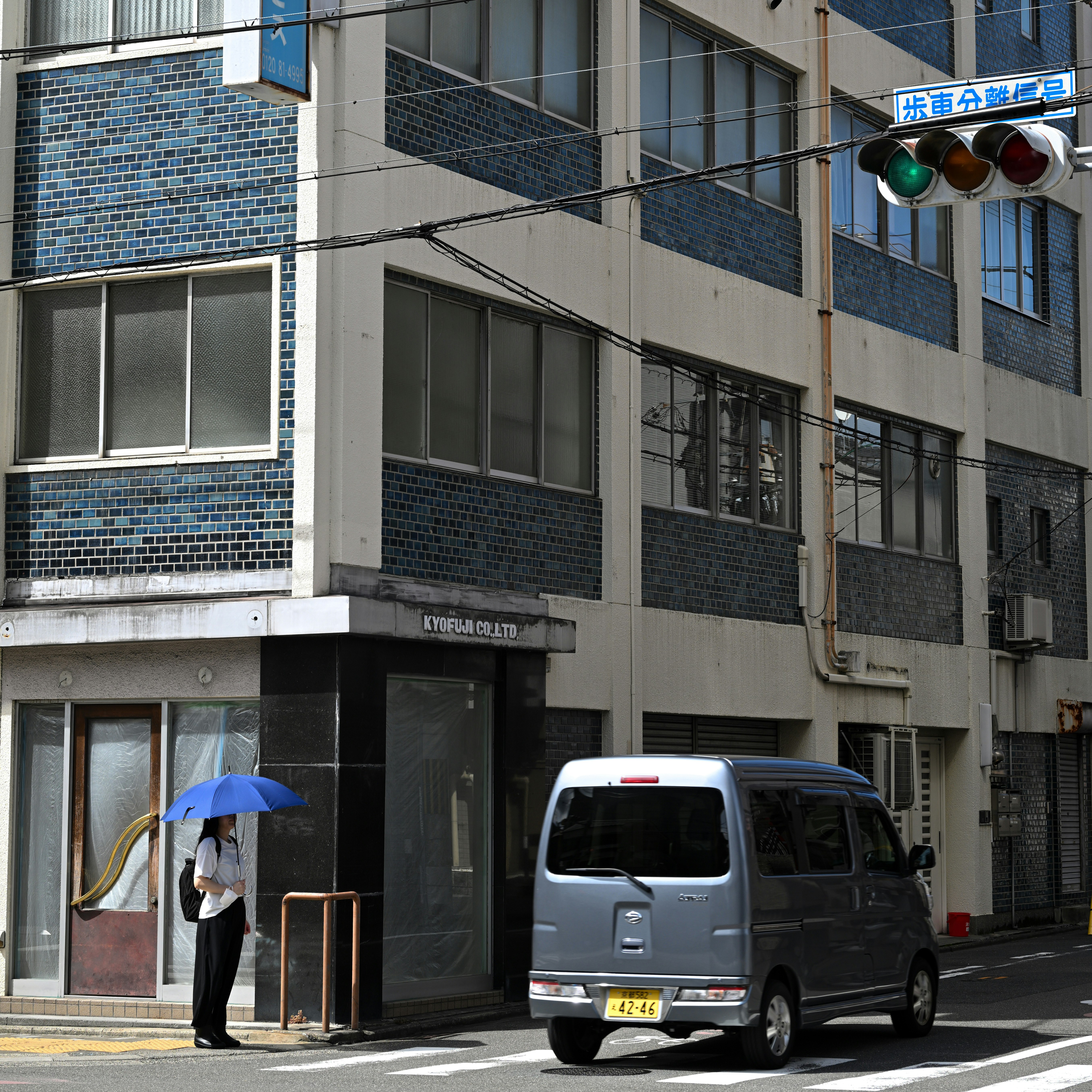 京都のビル街で赤信号と横断歩道、日傘の人
