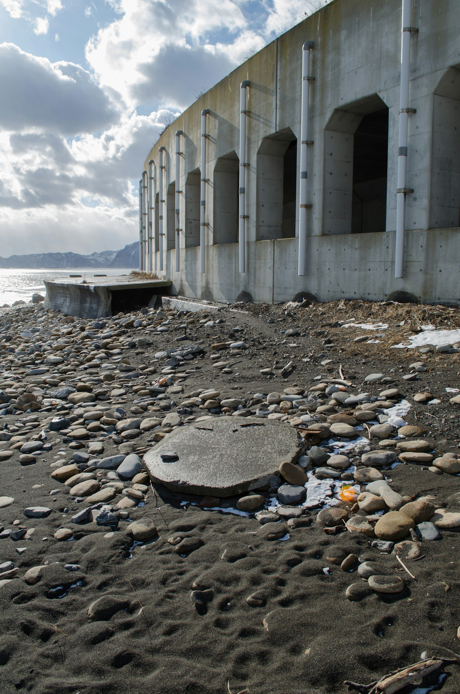 Coastal view featuring a concrete structure and scattered stones