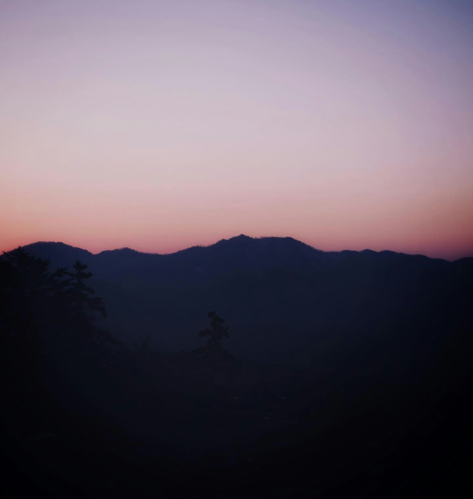 Siluet gunung saat senja dengan warna langit gradasi