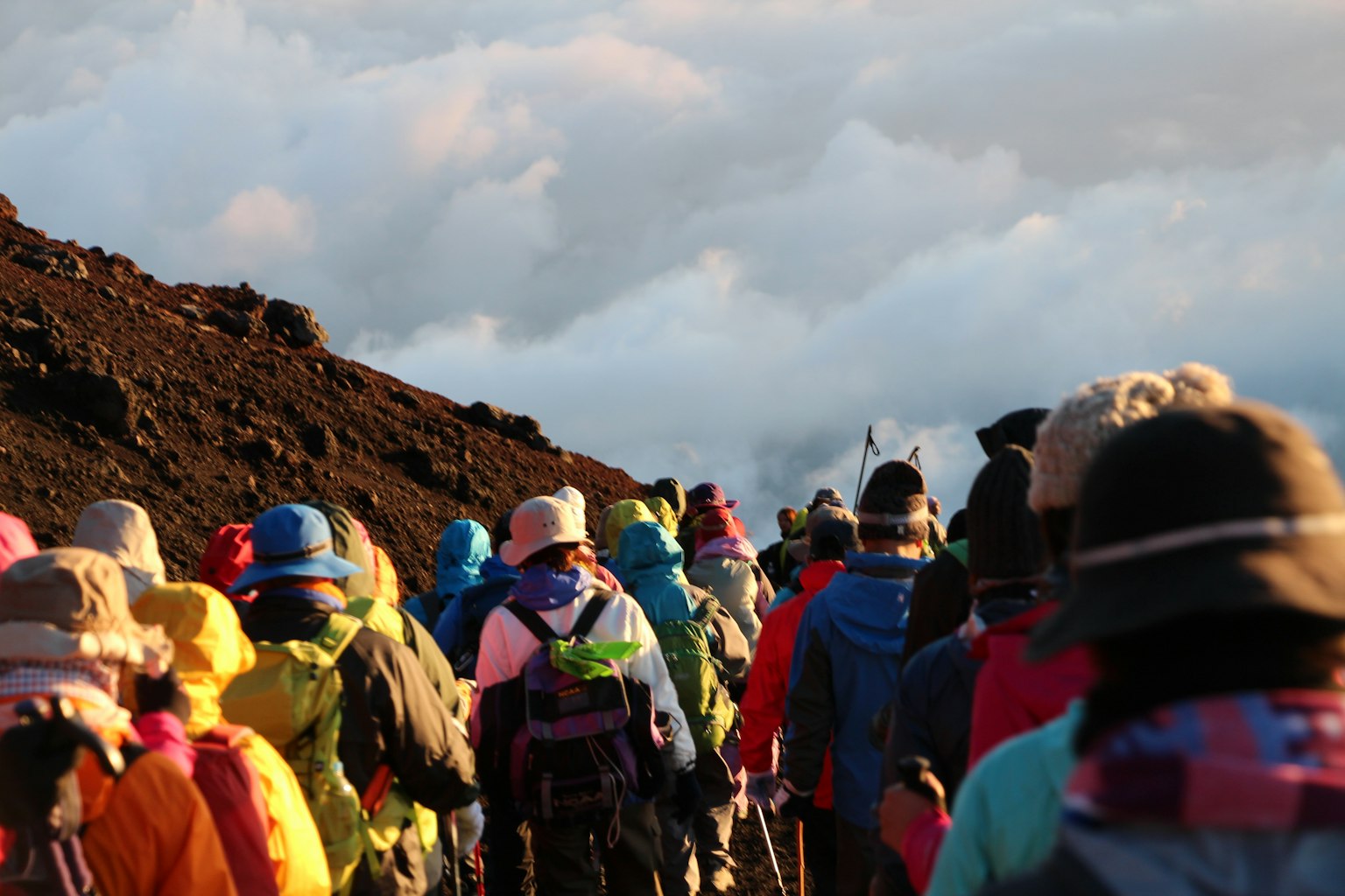 Un groupe d'escaladeurs montant une montagne vestes et chapeaux colorés visibles