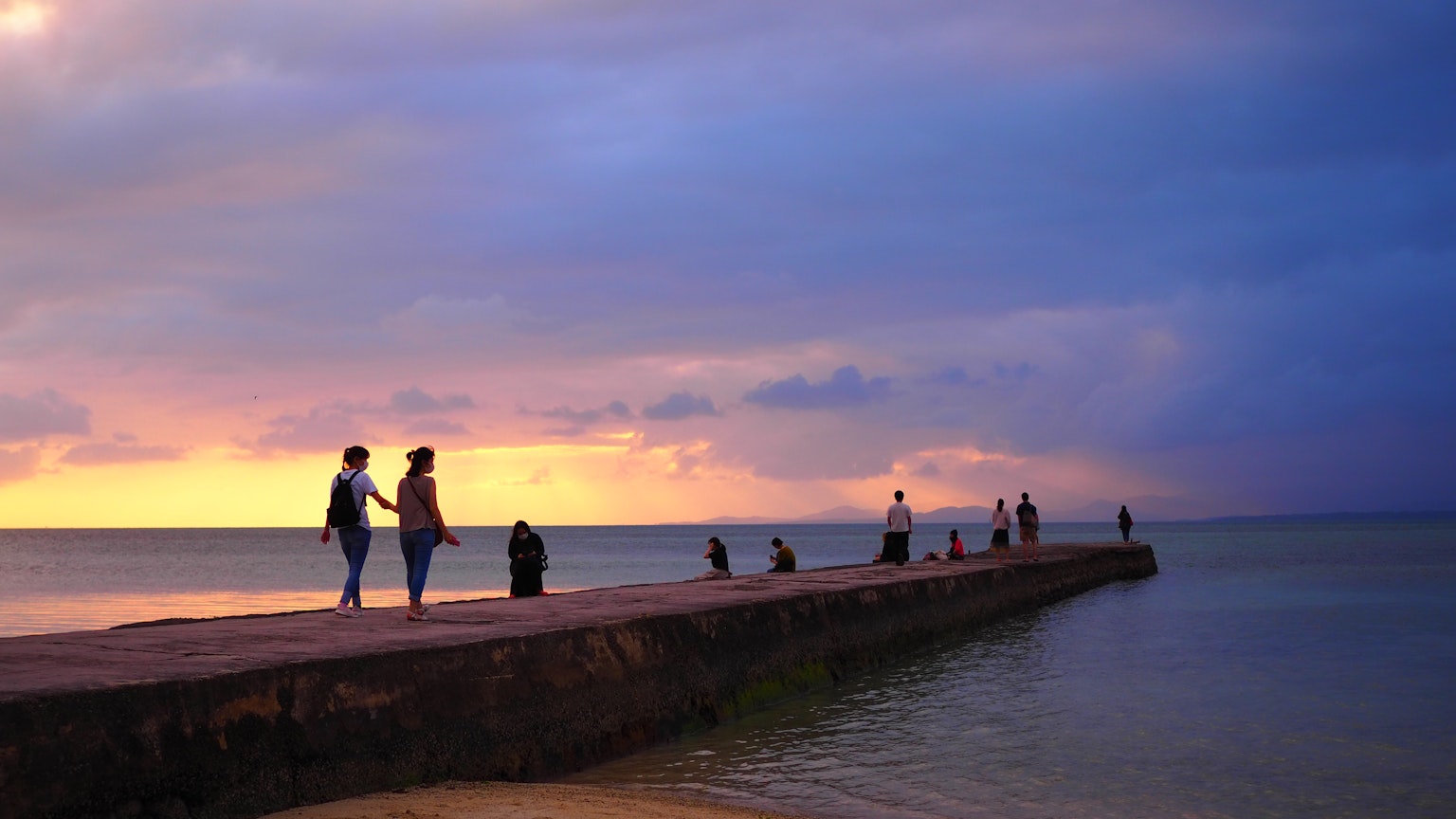 Menschen, die bei Sonnenuntergang auf einem Pier am Meer spazieren