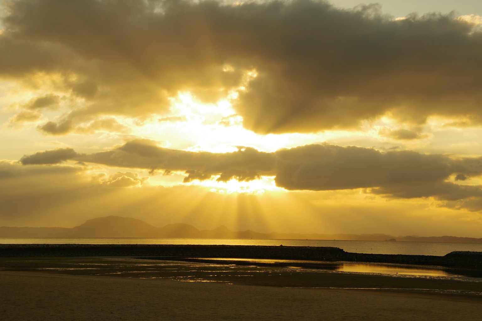 Bellissimi raggi di sole al tramonto che filtrano tra le nuvole e si riflettono sul mare