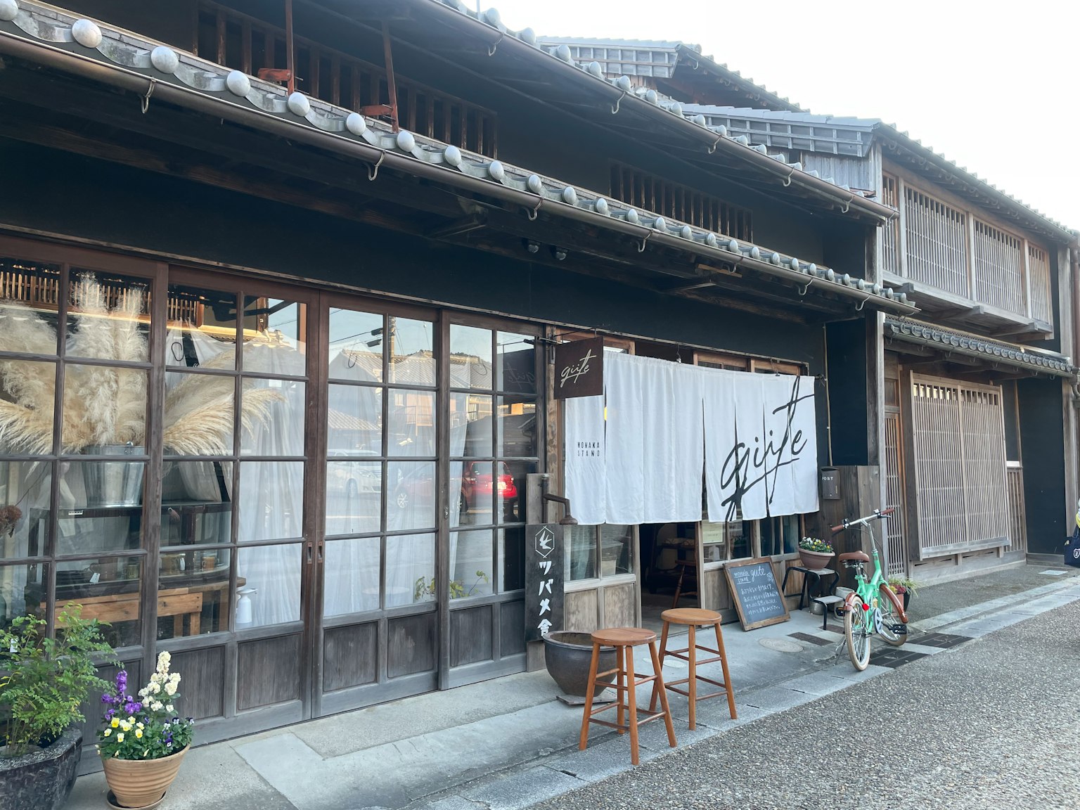 Extérieur d'un bâtiment japonais traditionnel avec des fenêtres en verre et un rideau noren blanc