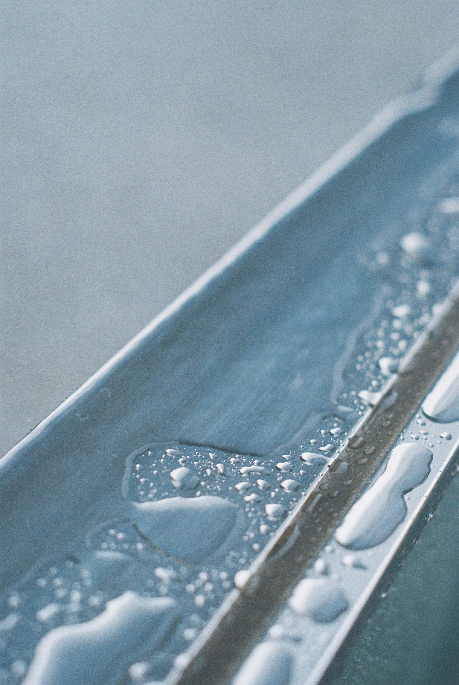 close-up of a thin edge with water droplets and bubbles on blue water