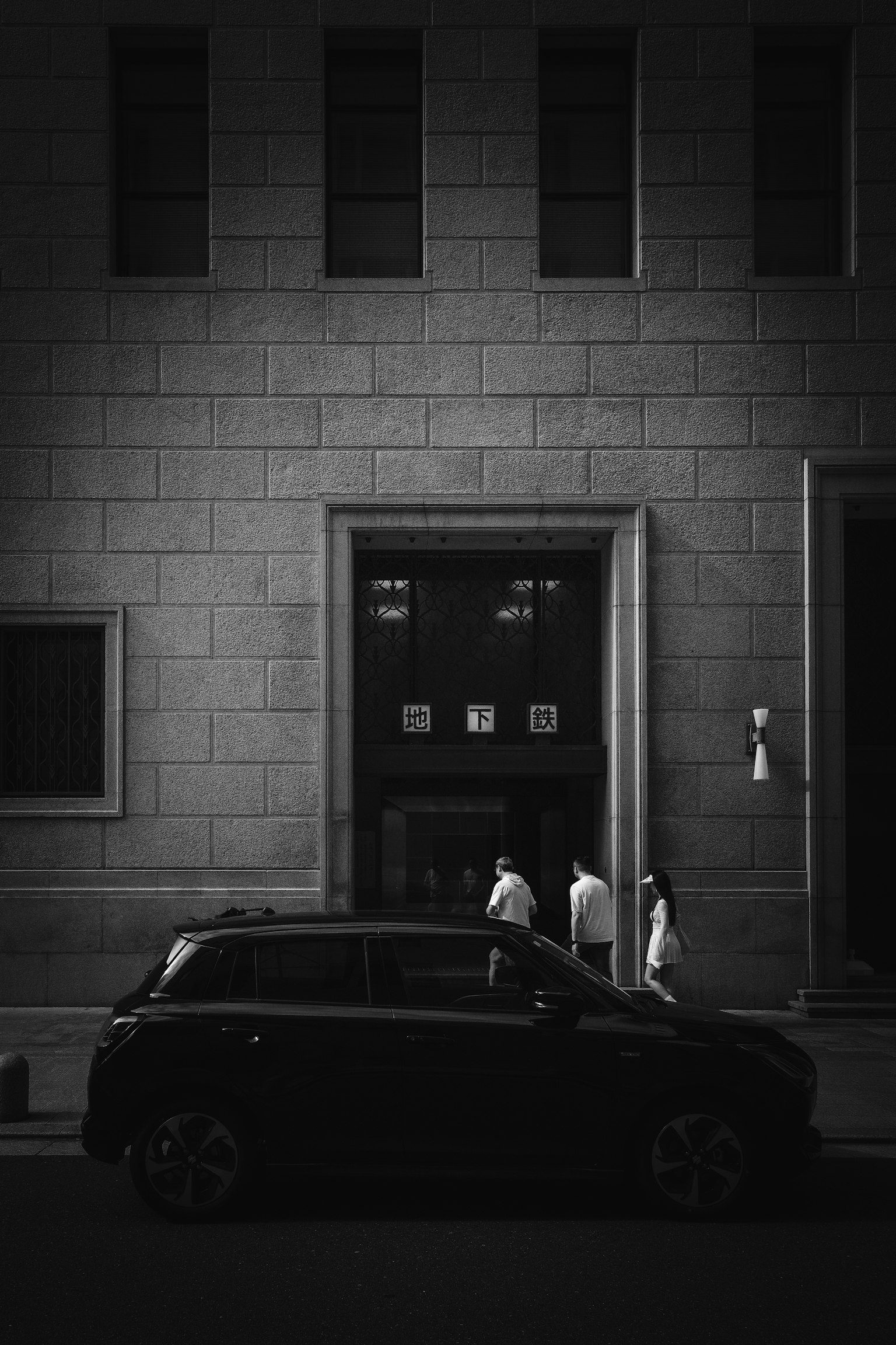 黒い車と建物の前を歩く人々のシルエット