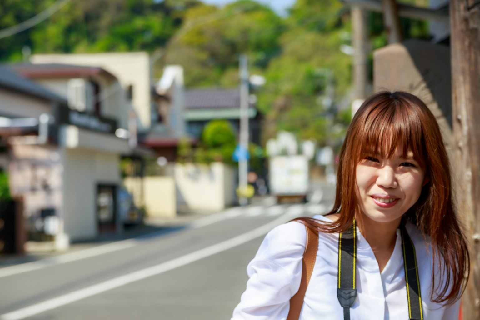 หญิงสาวยิ้มในแสงแดดสดใสกับถนนเงียบๆในพื้นหลัง