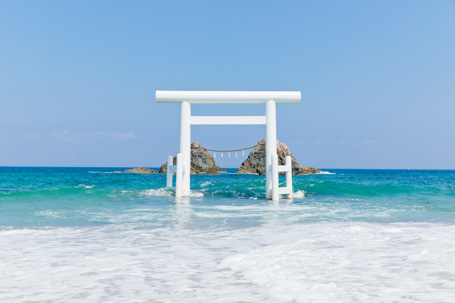 Portail torii blanc se tenant dans l'océan sous un ciel bleu