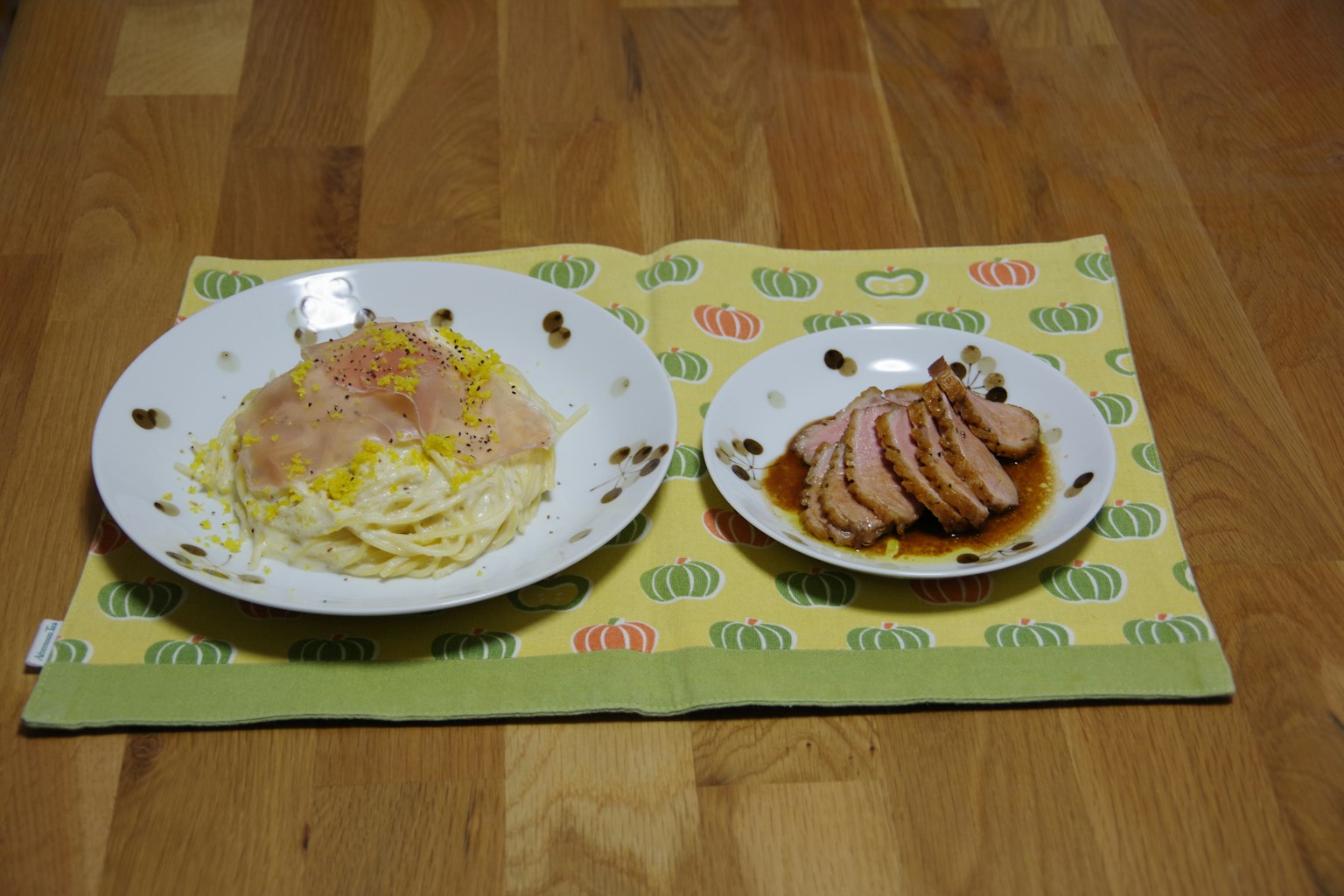 Kohl- und Schinken-Salat auf einem weißen Teller neben geschnittenem Fleisch mit Sauce auf einem anderen Teller