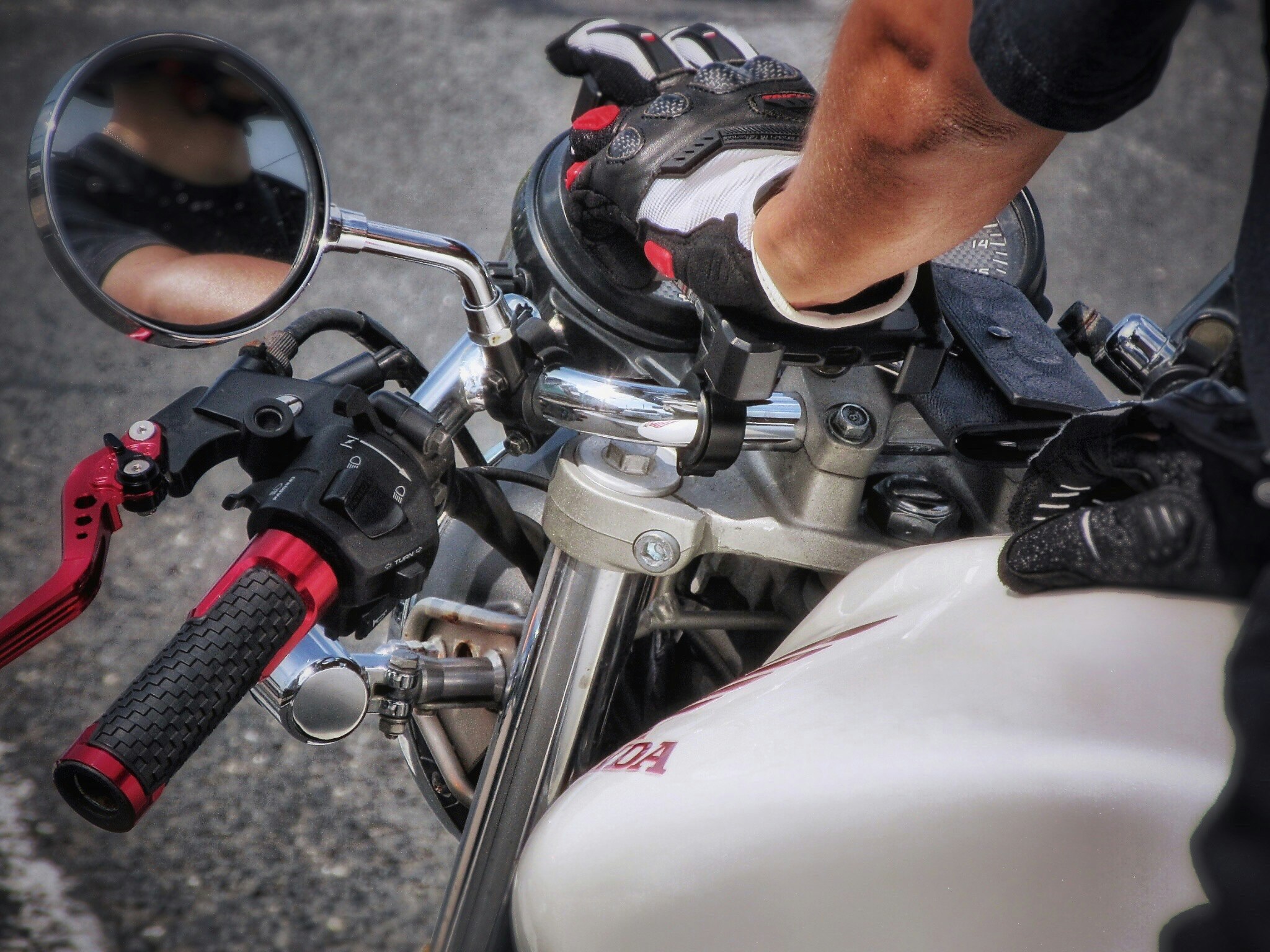 バイクのハンドルとライダーの手元が写る夏のツーリング風景