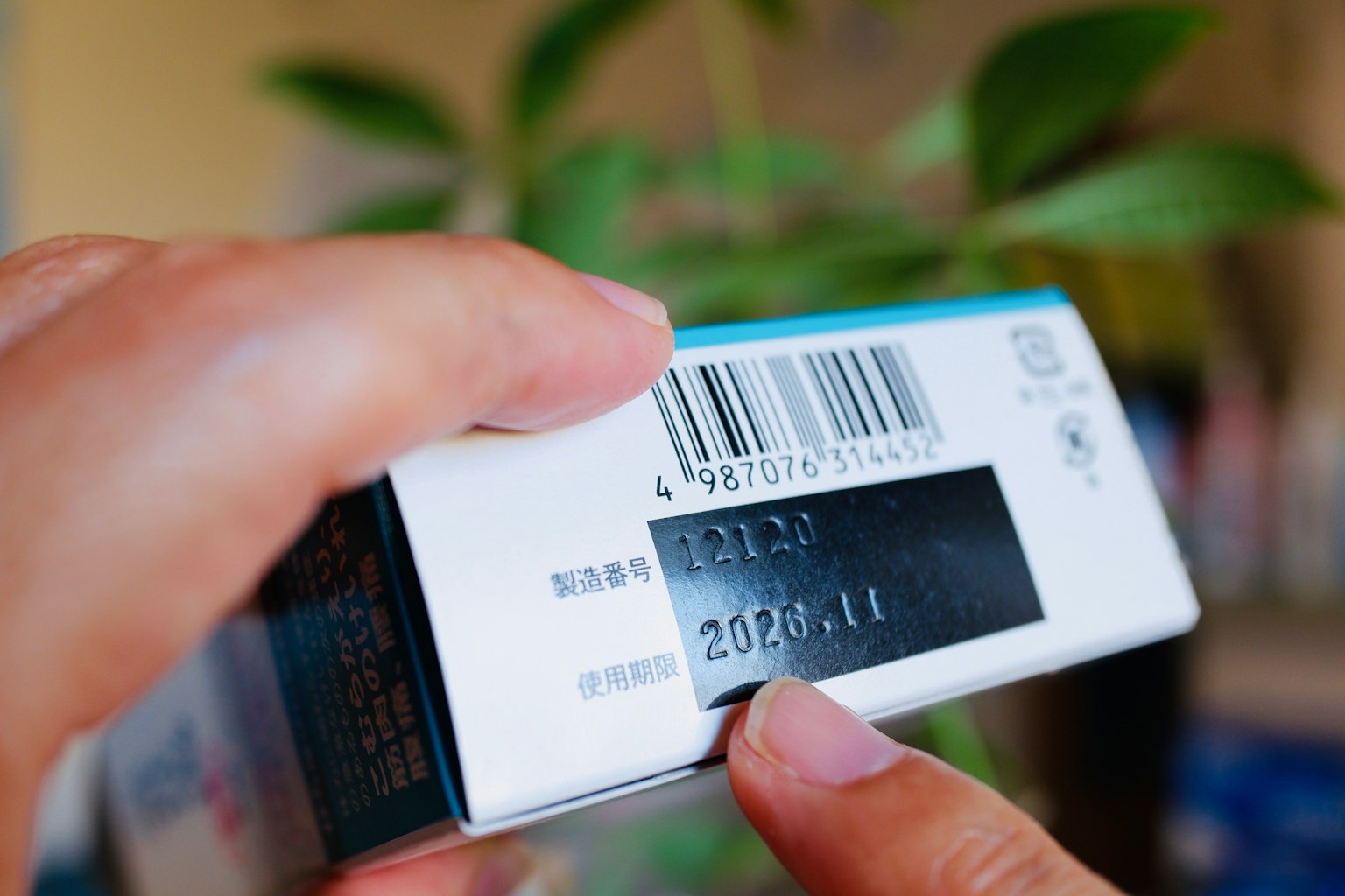 一隻手握著一個帶有條形碼和有效日期的產品包裝