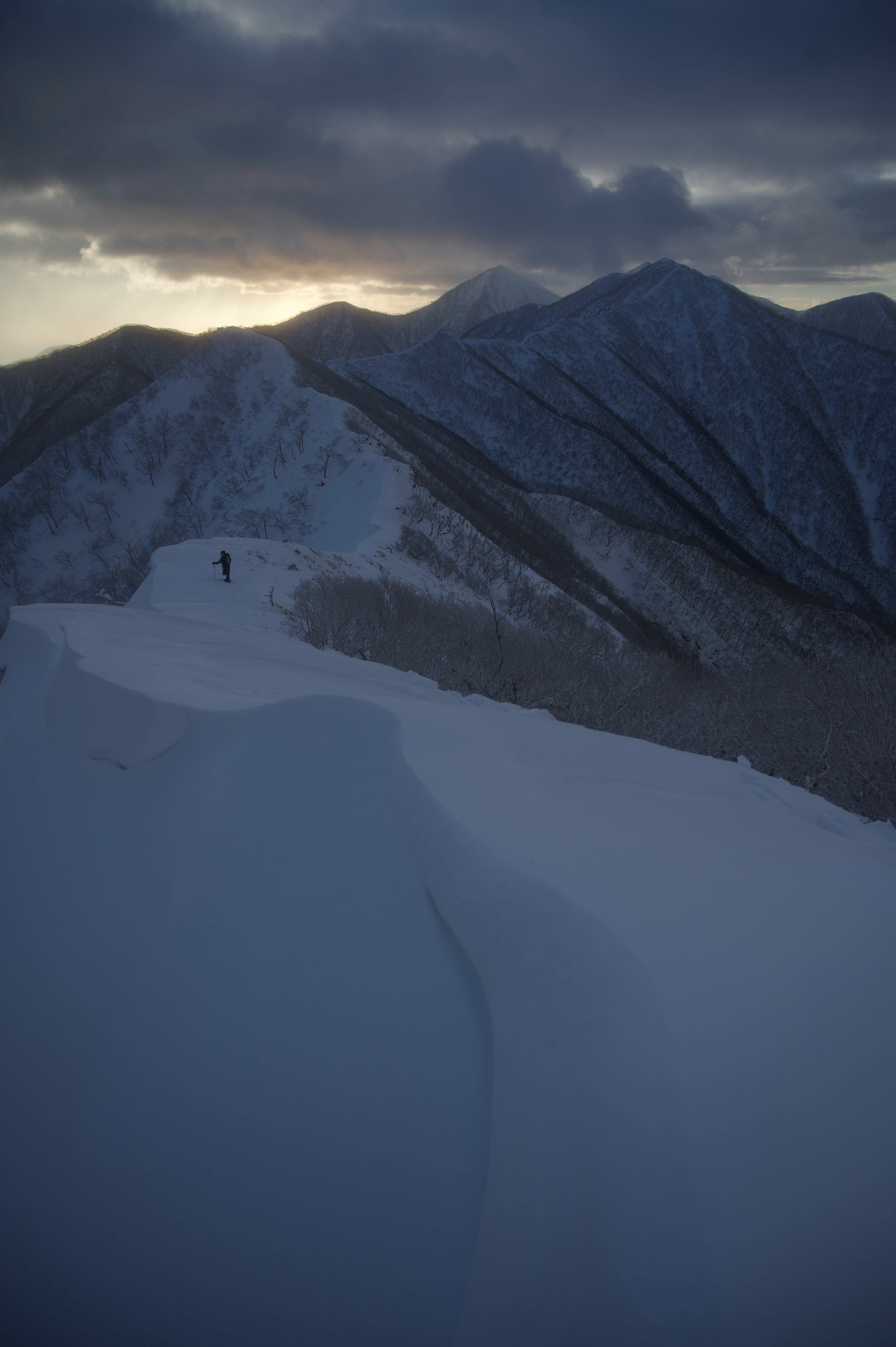 persone che camminano lungo una cresta innevata al crepuscolo