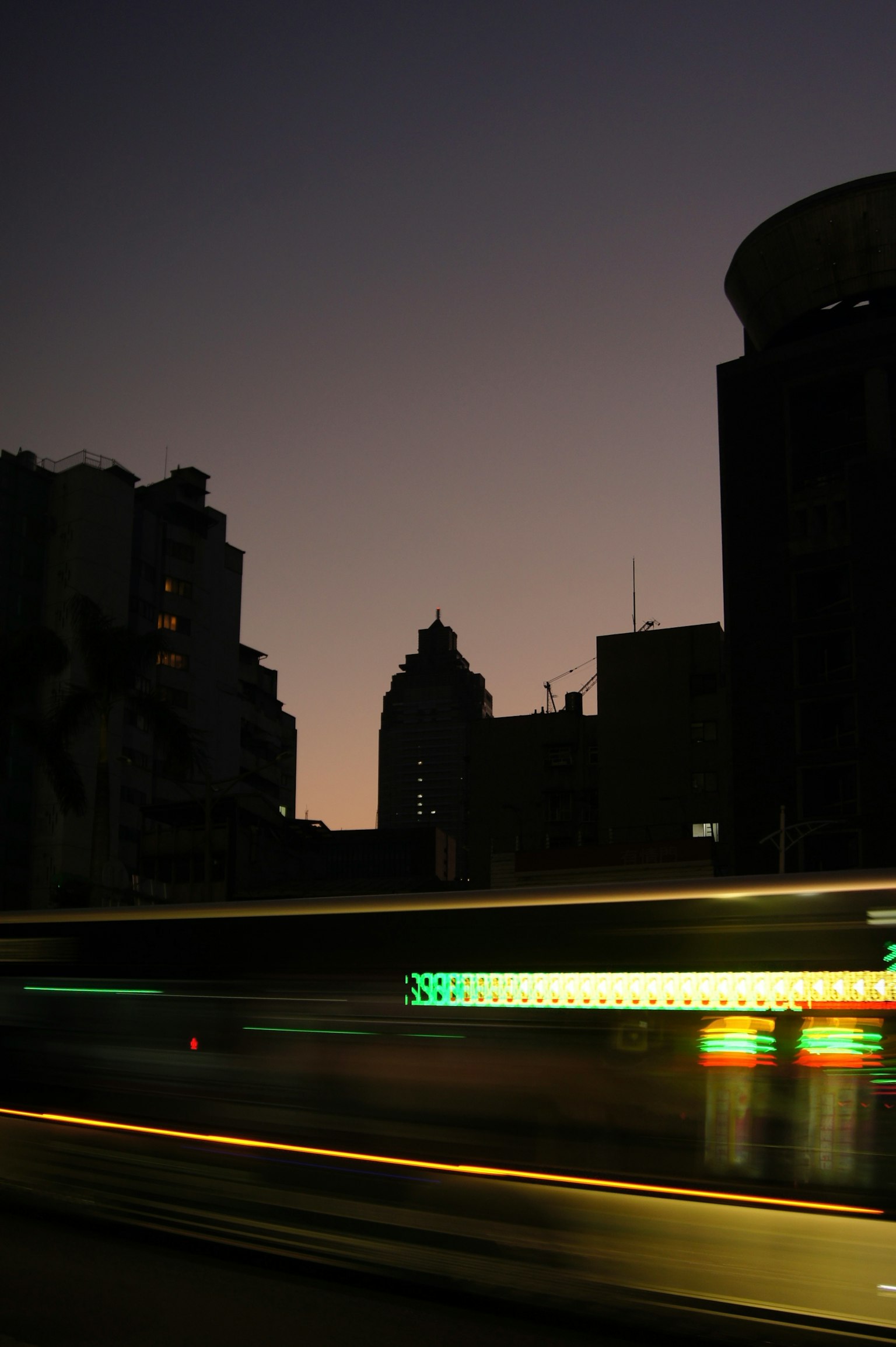 夕暮れ時の都市のシルエットと流れる光の軌跡
