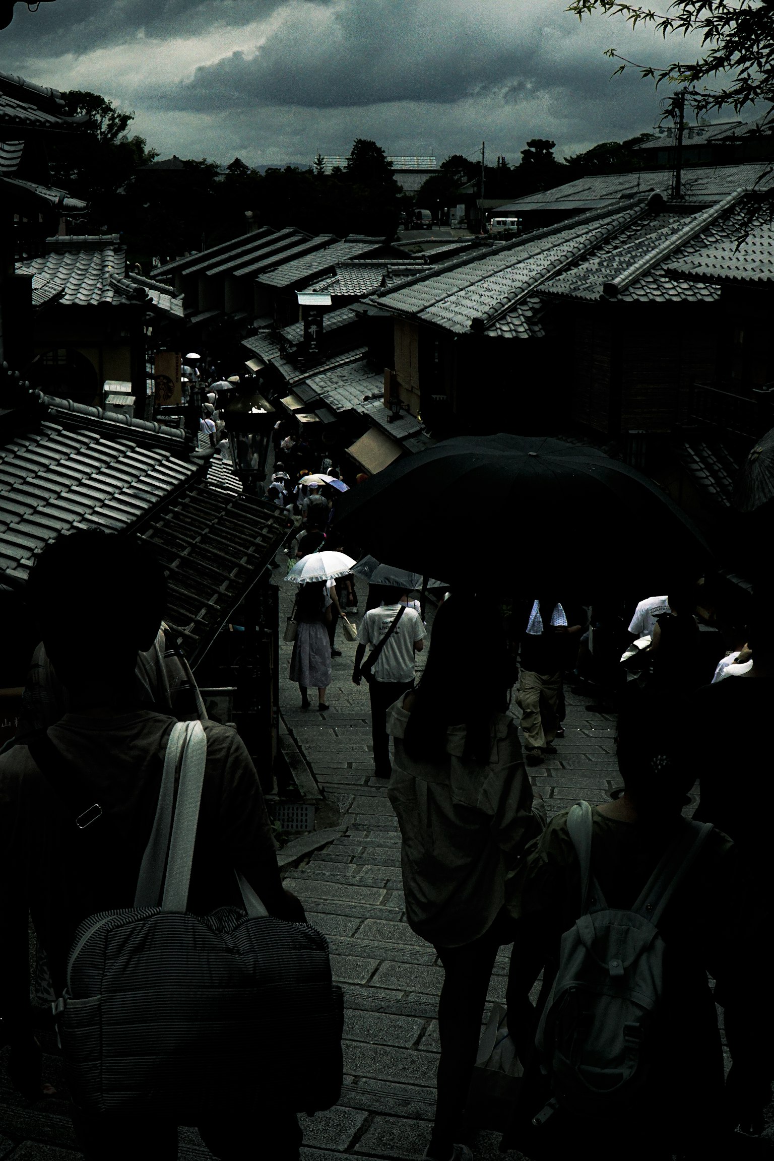 Foule avec des parapluies dans une rue sombre de Kyoto