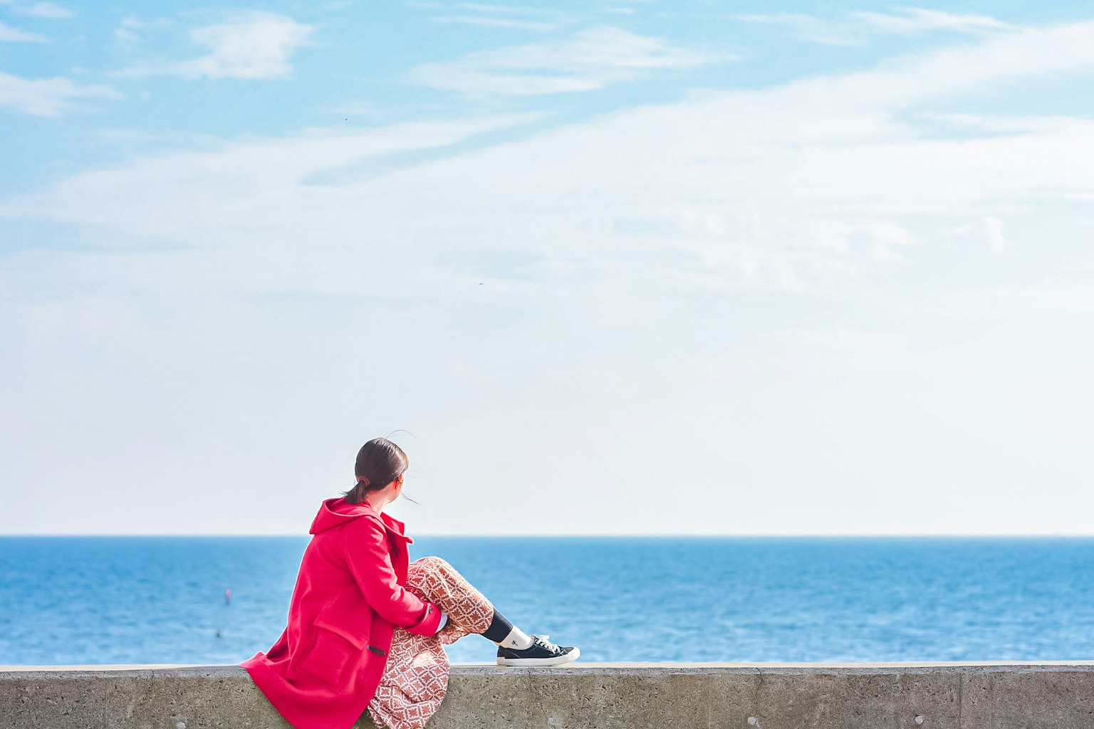 穿着红色外套的女人坐在海边